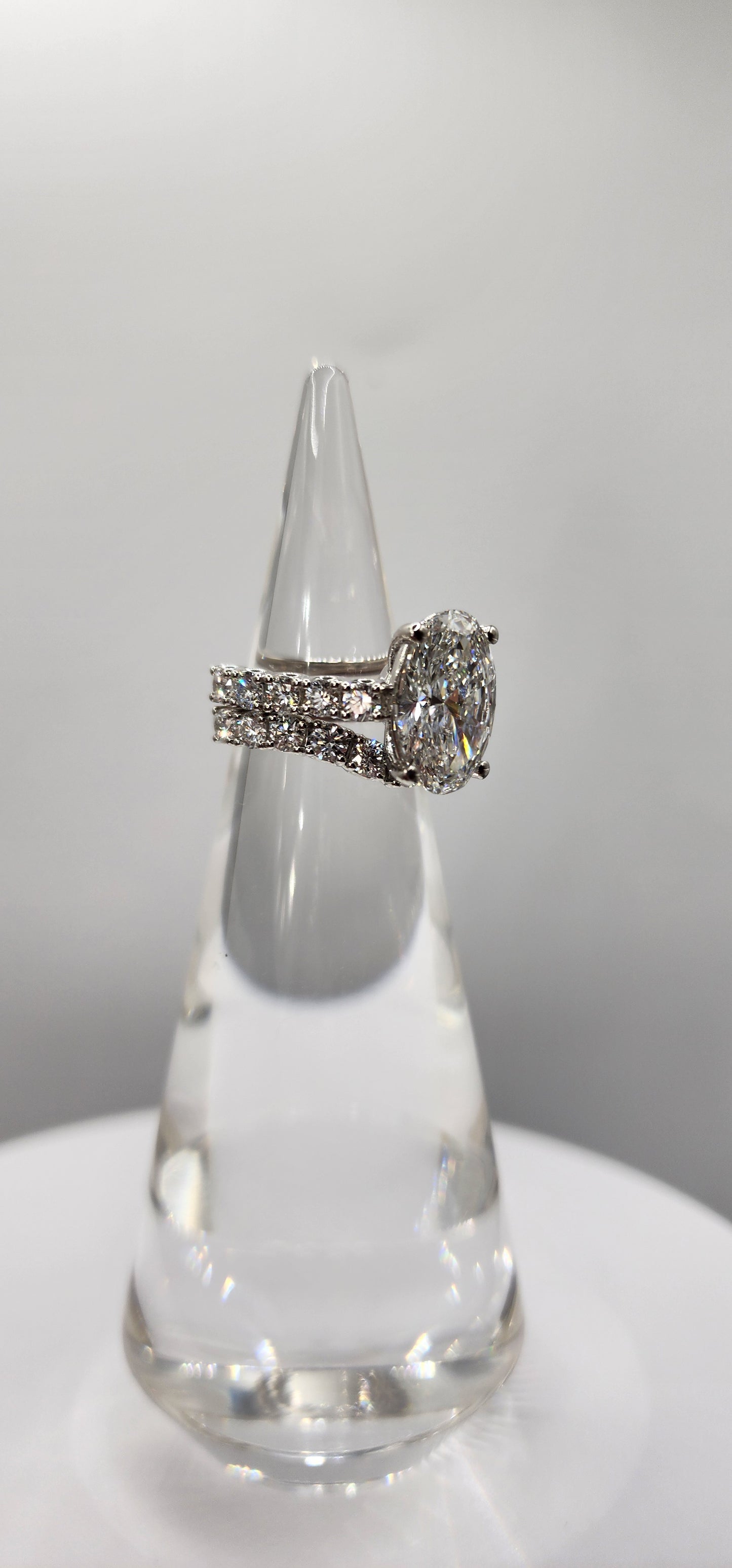 "The Marisol" is a 5 Carat Oval Lab Gown Diamond, F/VS1 set in 14k White Gold with Accent diamonds and a contoured wedding band