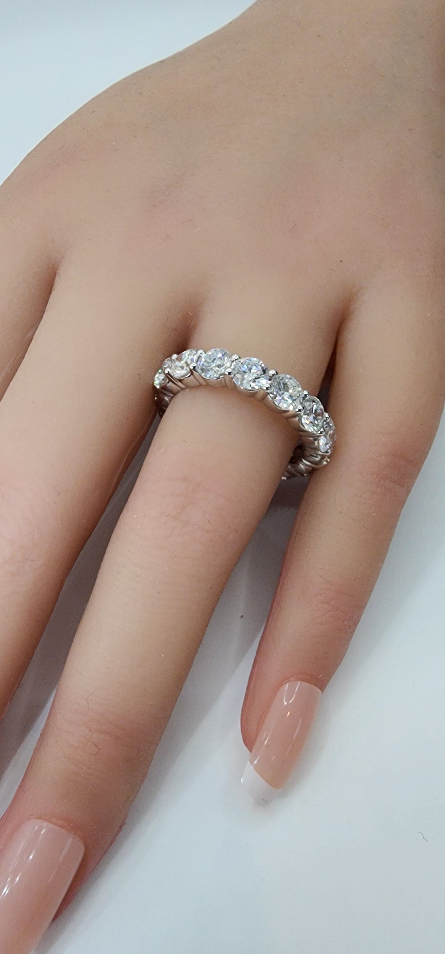 White gold ring with diamonds on a finger against a white background