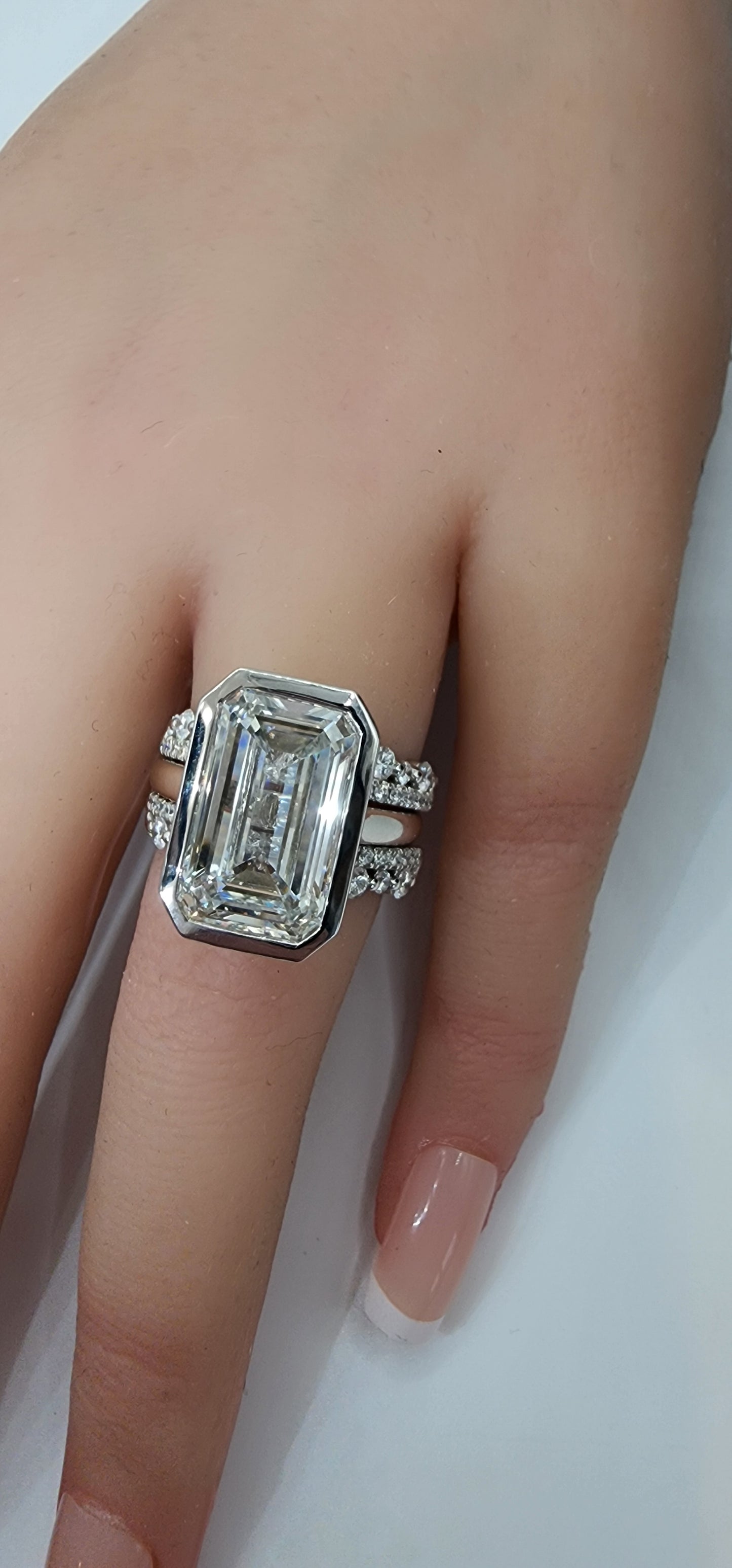 Diamond ring on a finger against a neutral background