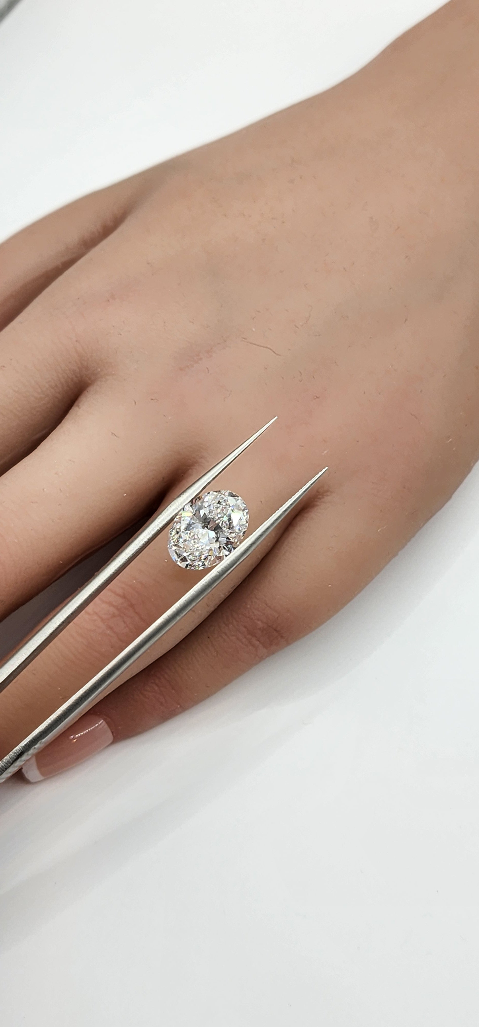 Diamond ring being held with tweezers against a white background
