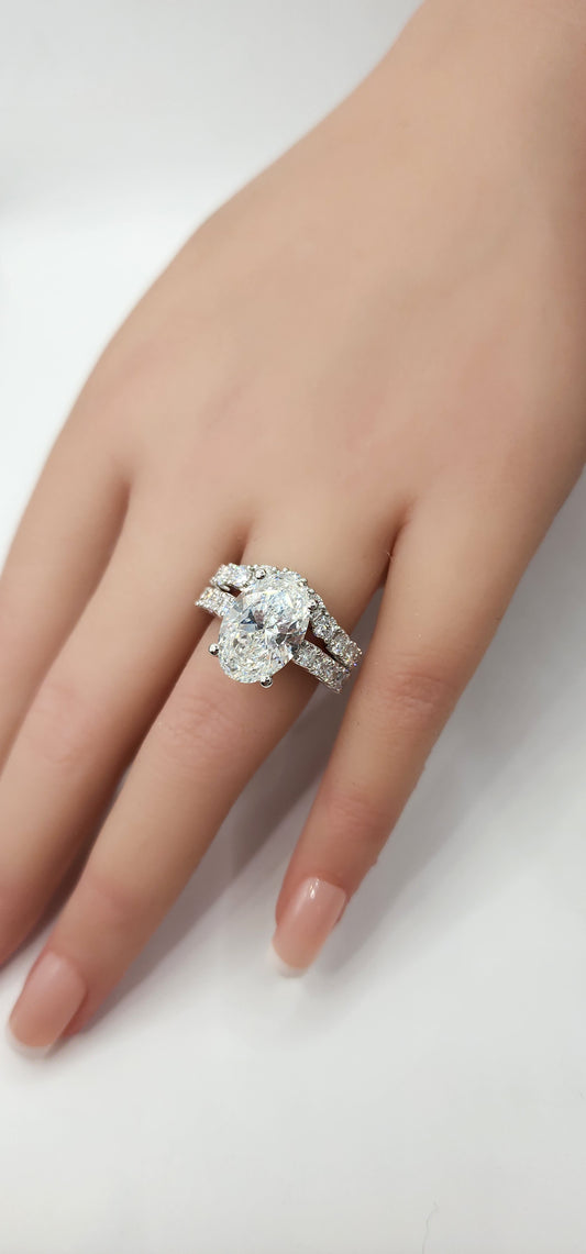 "The Marisol" is a 5 Carat Oval Lab Gown Diamond, F/VS1 set in 14k White Gold with Accent diamonds and a contoured wedding band