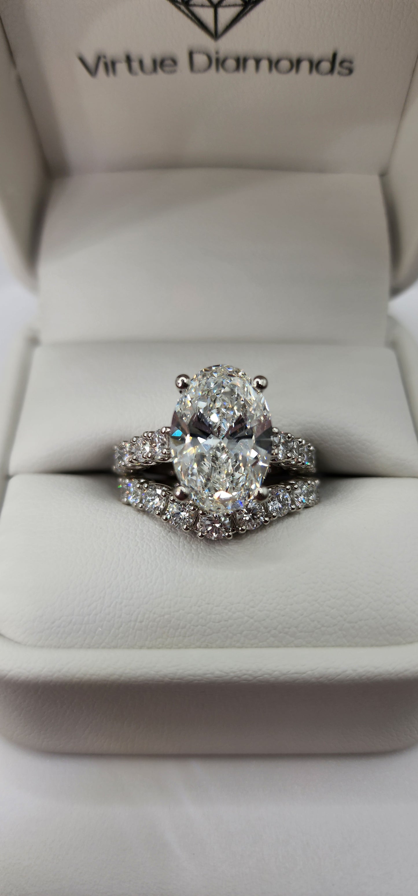 "The Marisol" is a 5 Carat Oval Lab Gown Diamond, F/VS1 set in 14k White Gold with Accent diamonds and a contoured wedding band