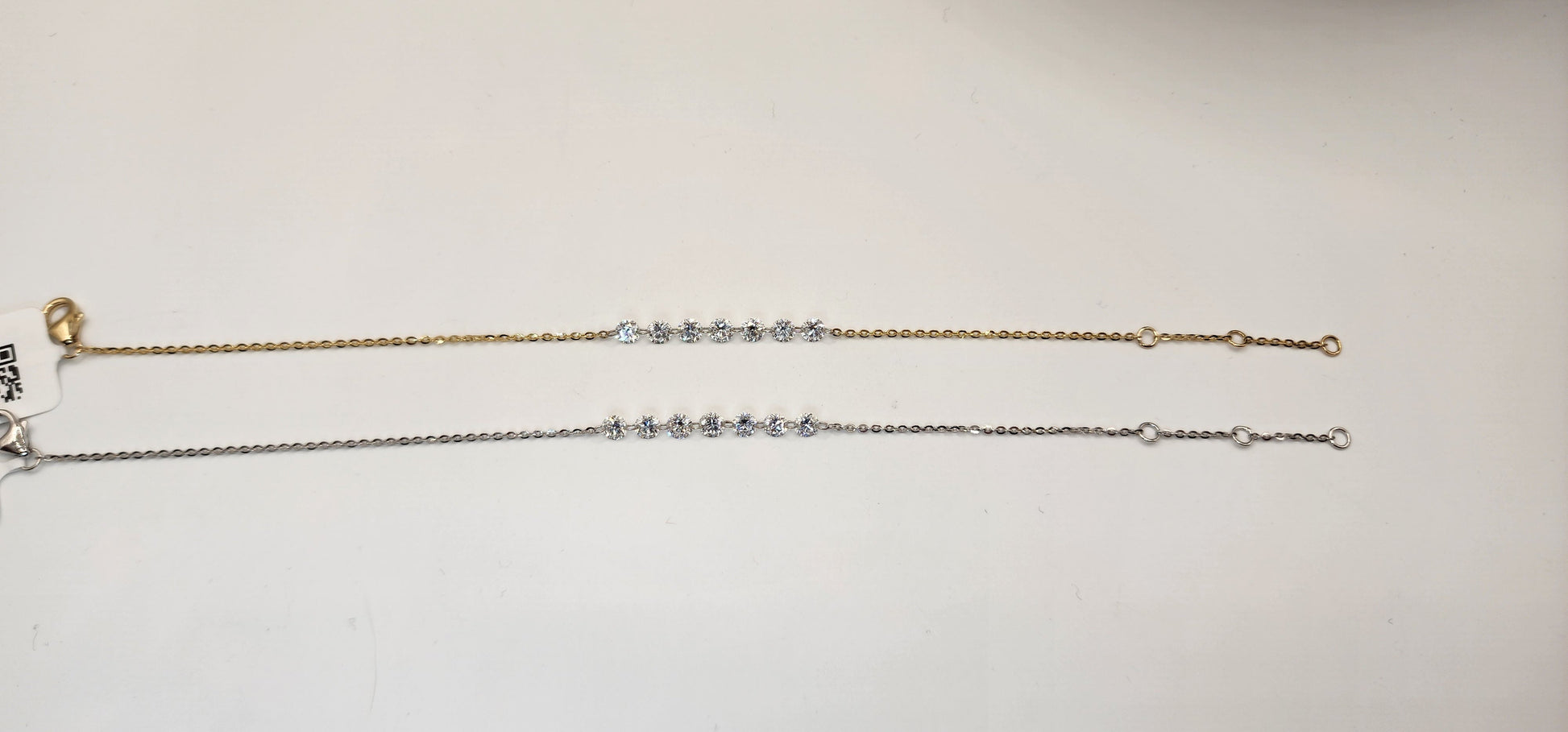 Two gold and white gold diamond bracelets on a light gray background