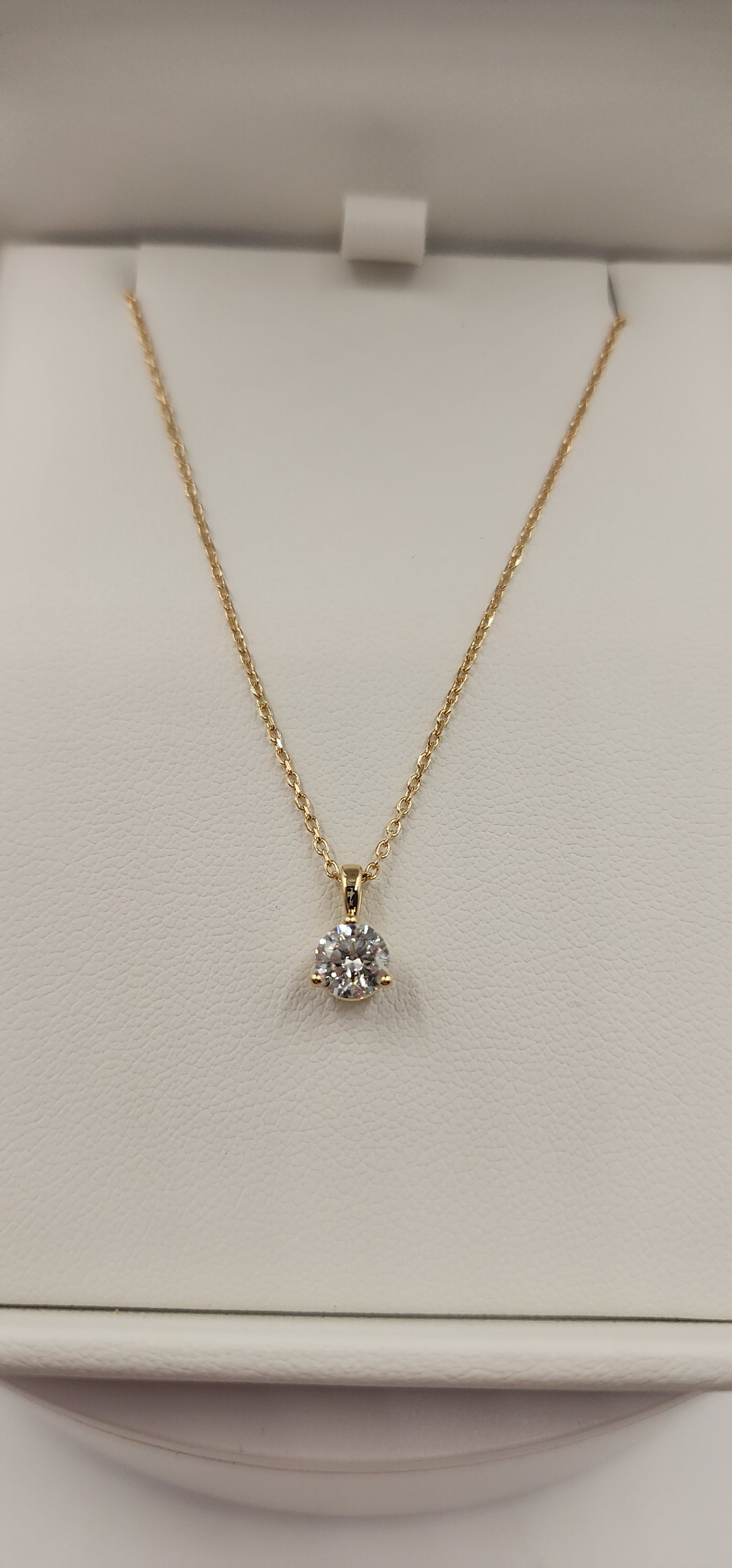 Gold necklace with a diamond pendant on a light beige background