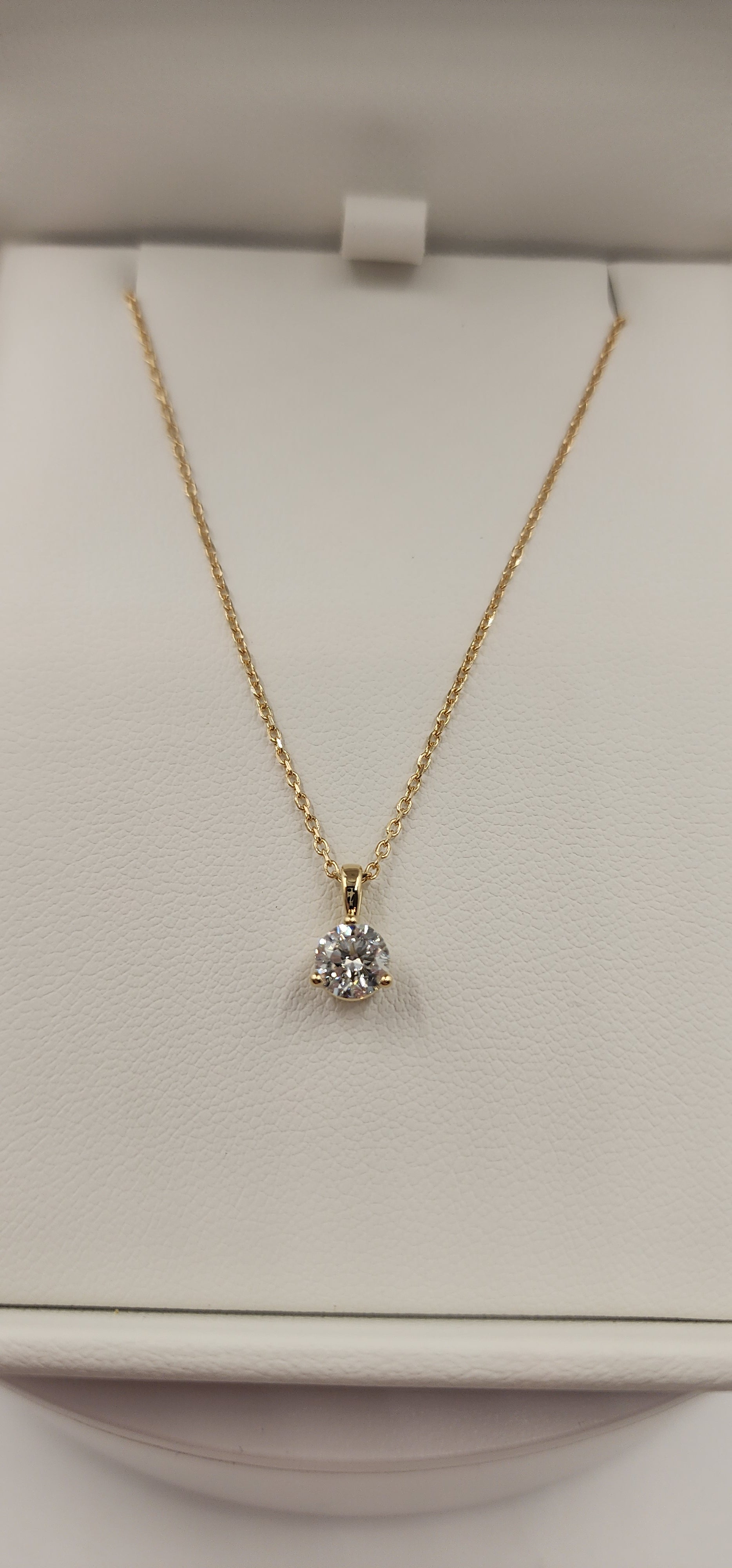 Gold necklace with a diamond pendant on a light beige background
