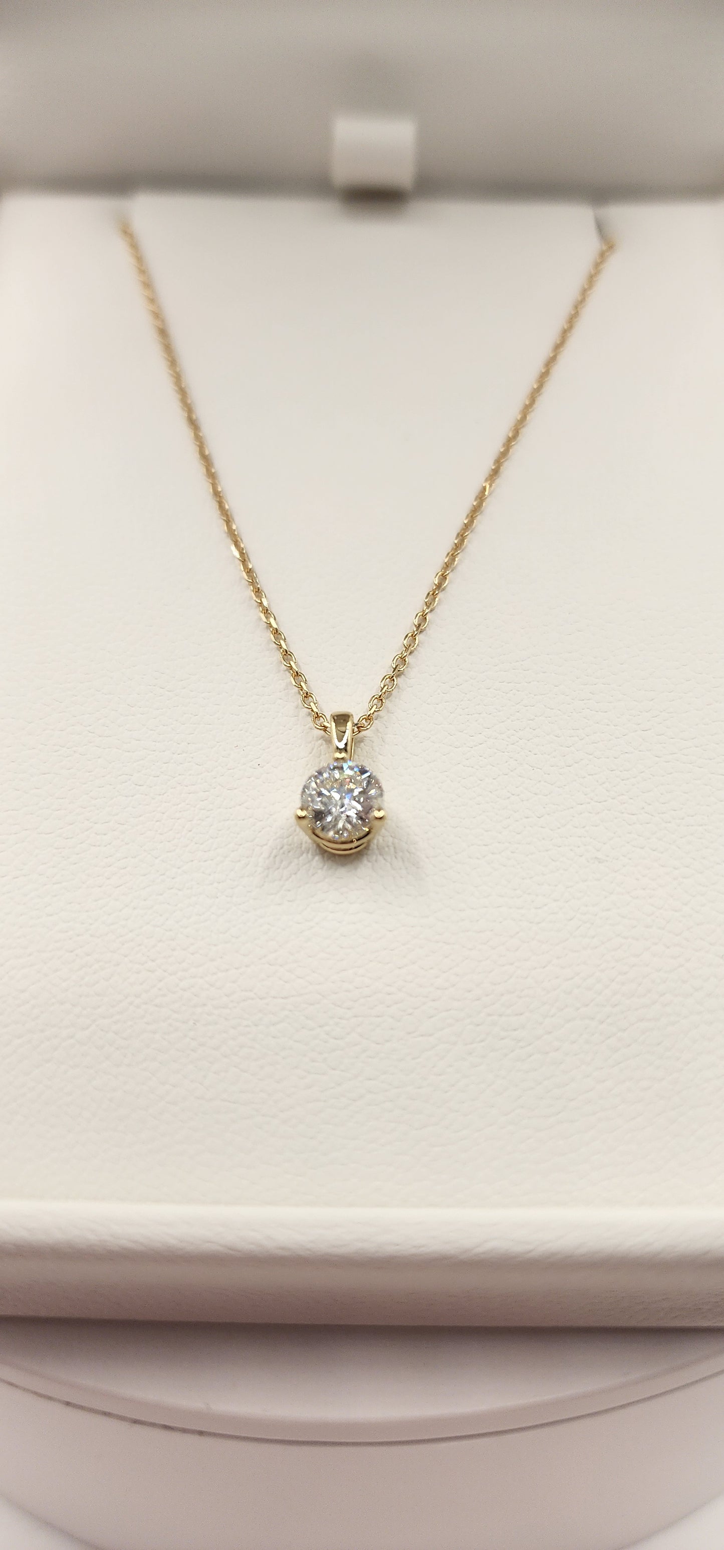 Gold necklace with a diamond pendant on a white cushion