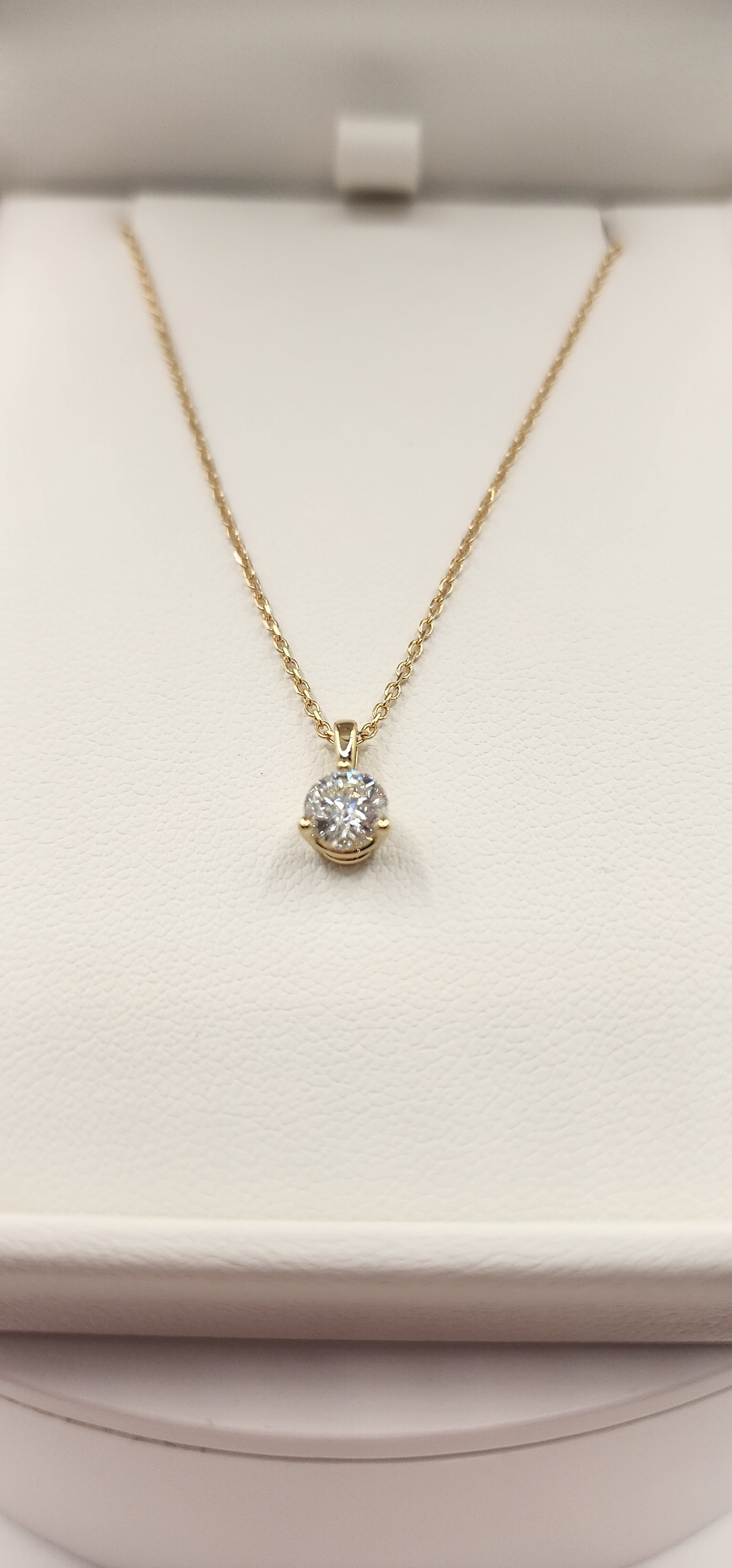 Gold necklace with a diamond pendant on a white cushion