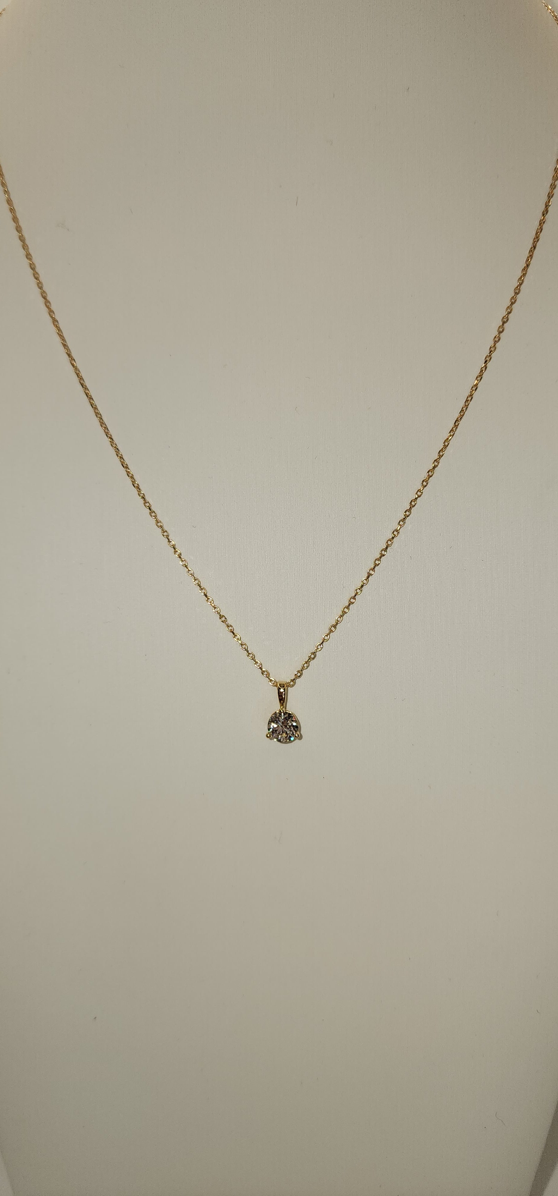 Gold necklace with a small pendant on a light gray background
