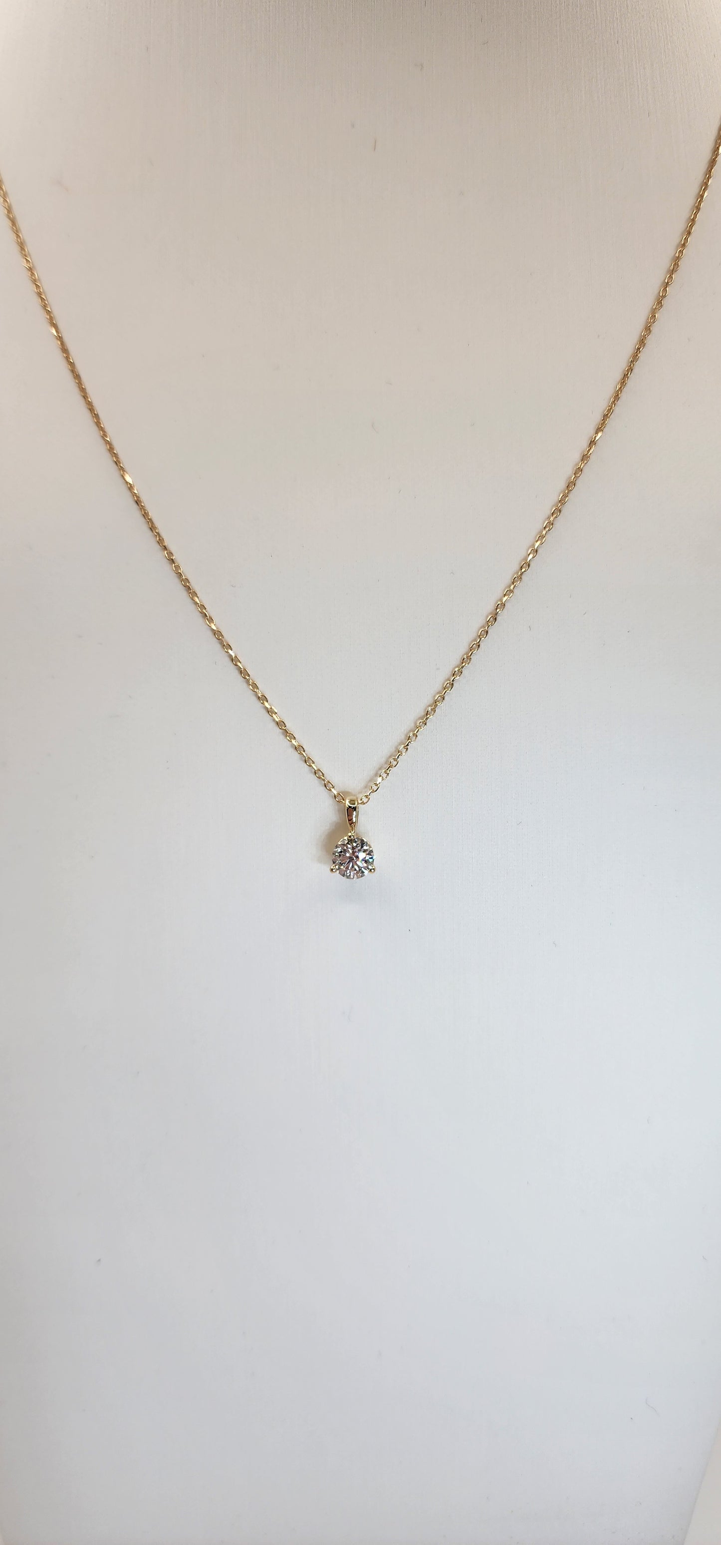 Gold necklace with a small pendant on a light background