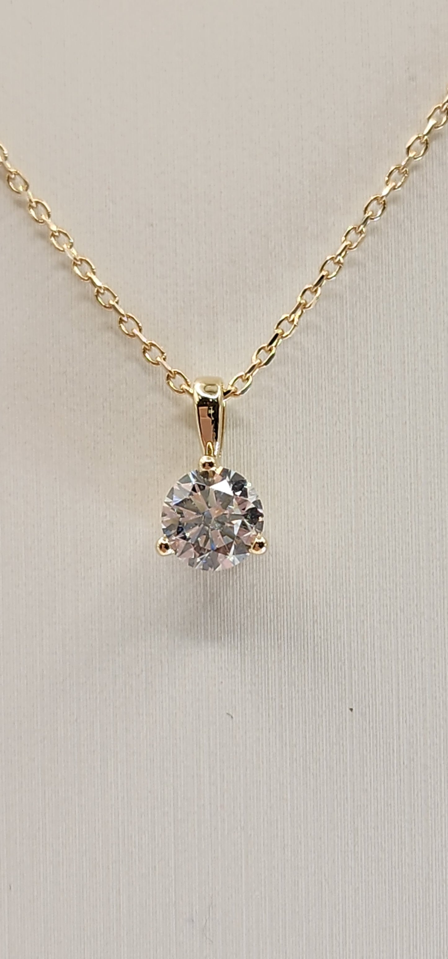 Gold necklace with a diamond pendant on a light gray background