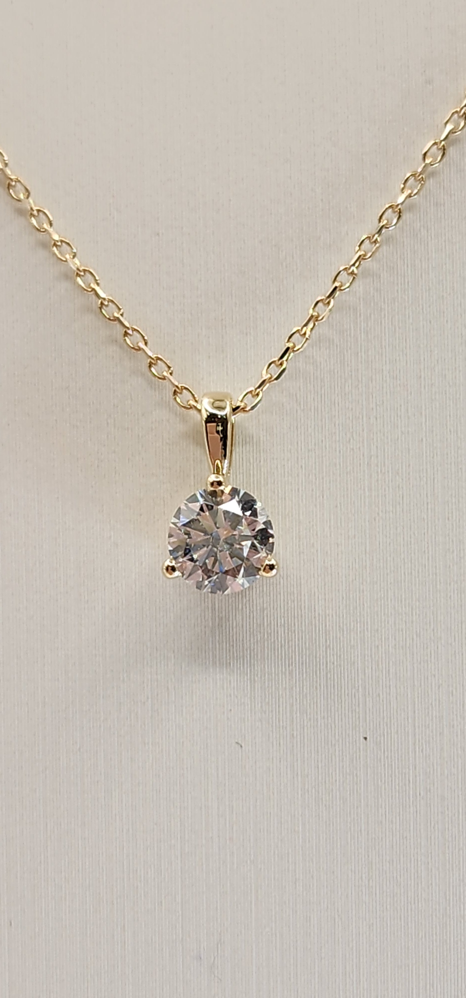 Gold necklace with a diamond pendant on a light gray background