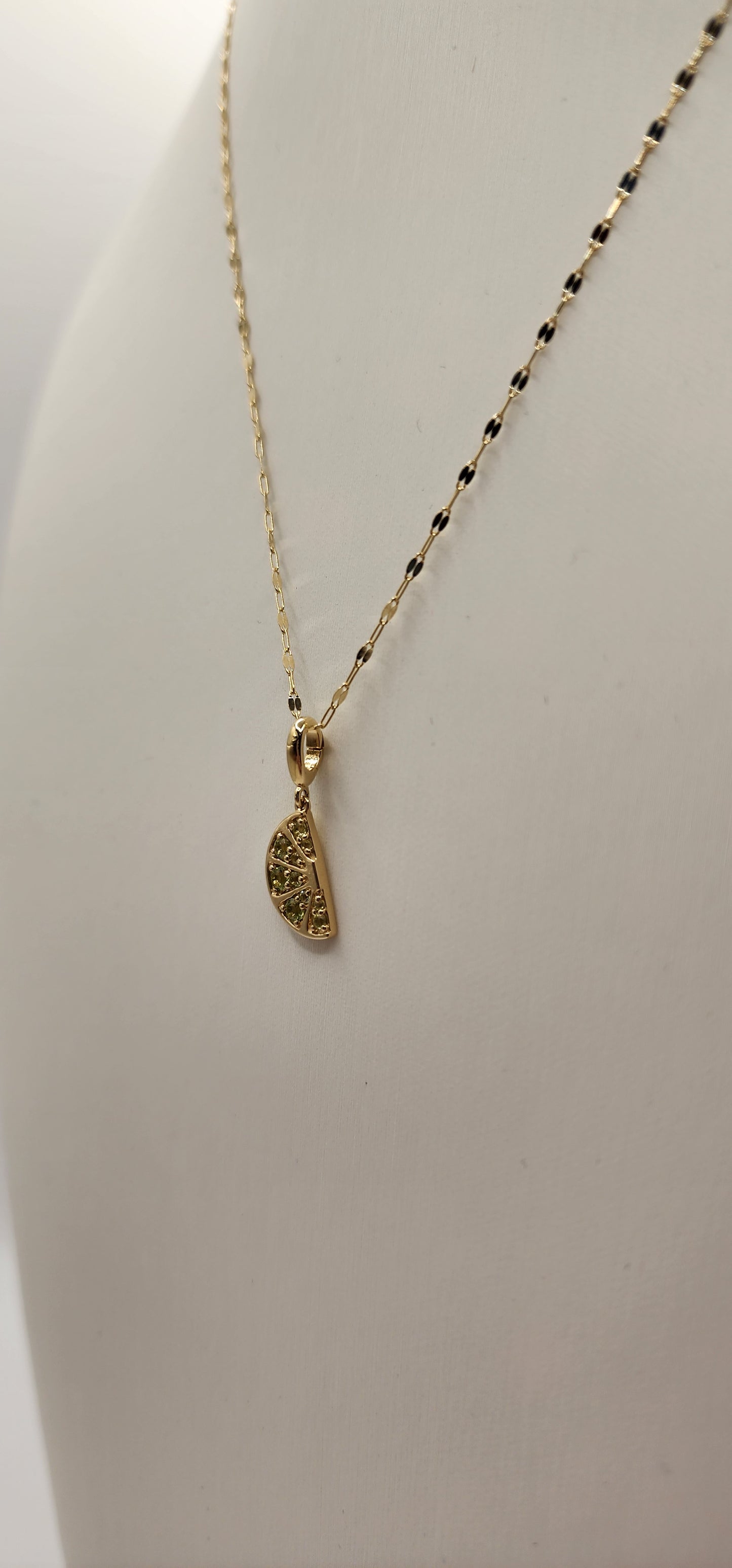 Gold necklace with a pendant on a light gray background