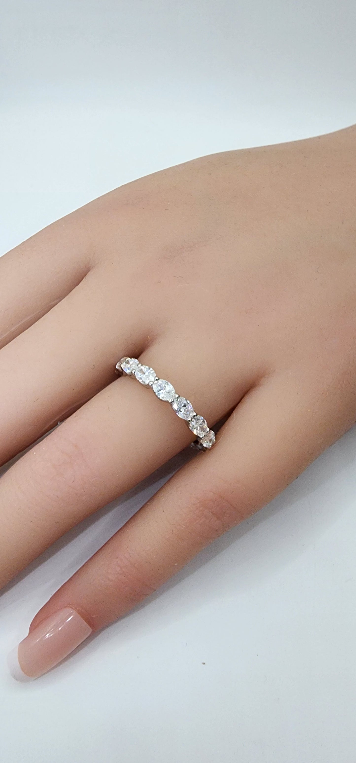 Close-up of a hand wearing a diamond ring on a light background