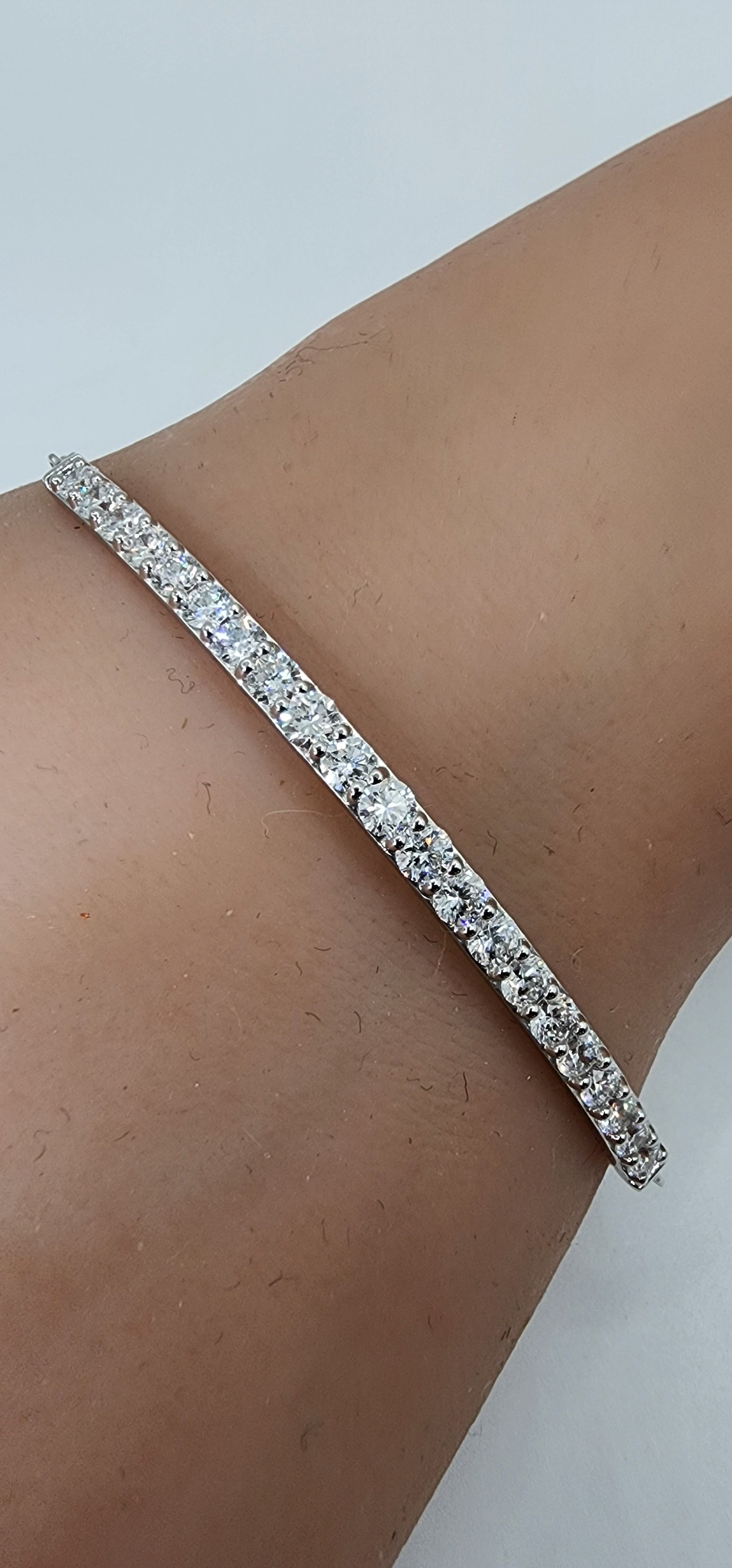 White Gold and Diamond bracelet on a persons wrist in front of a white background