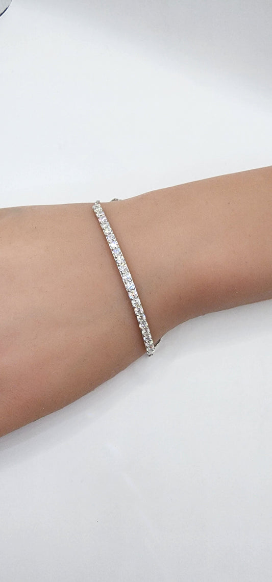 White gold and diamond bracelet on a persons wrist against a white back drop