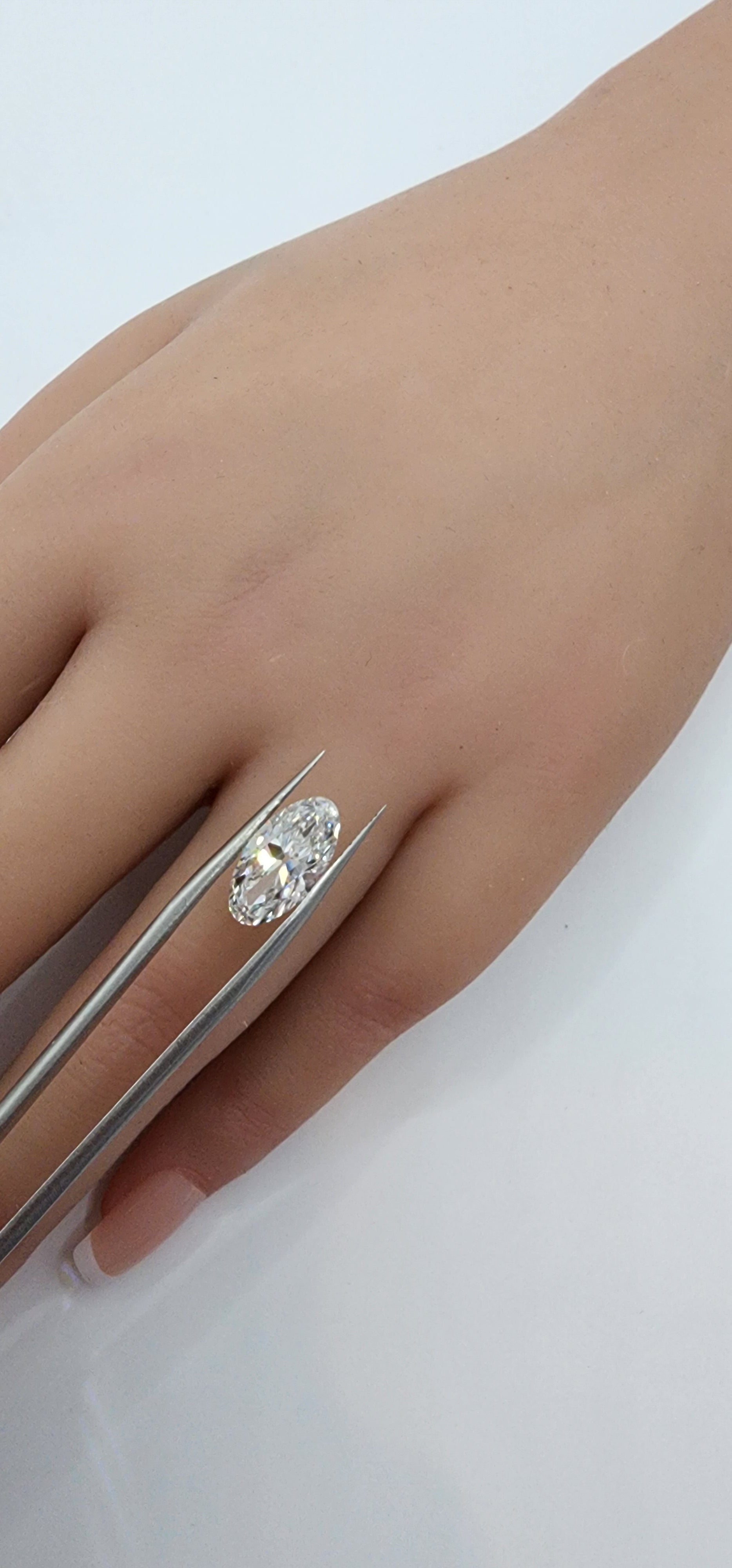 Hand wearing a silver ring with a clear gemstone on a light gray background