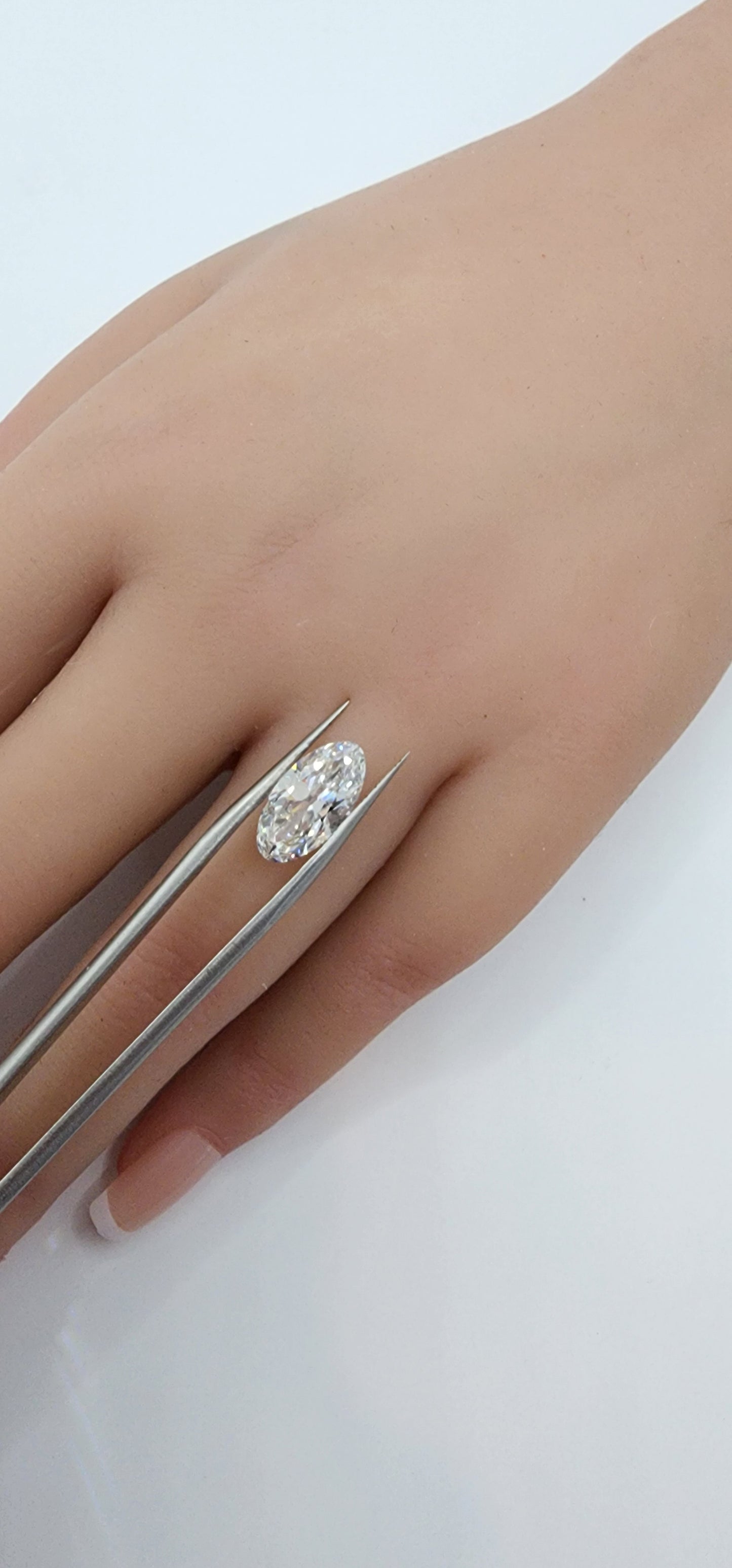 Hand wearing a diamond ring on a light background