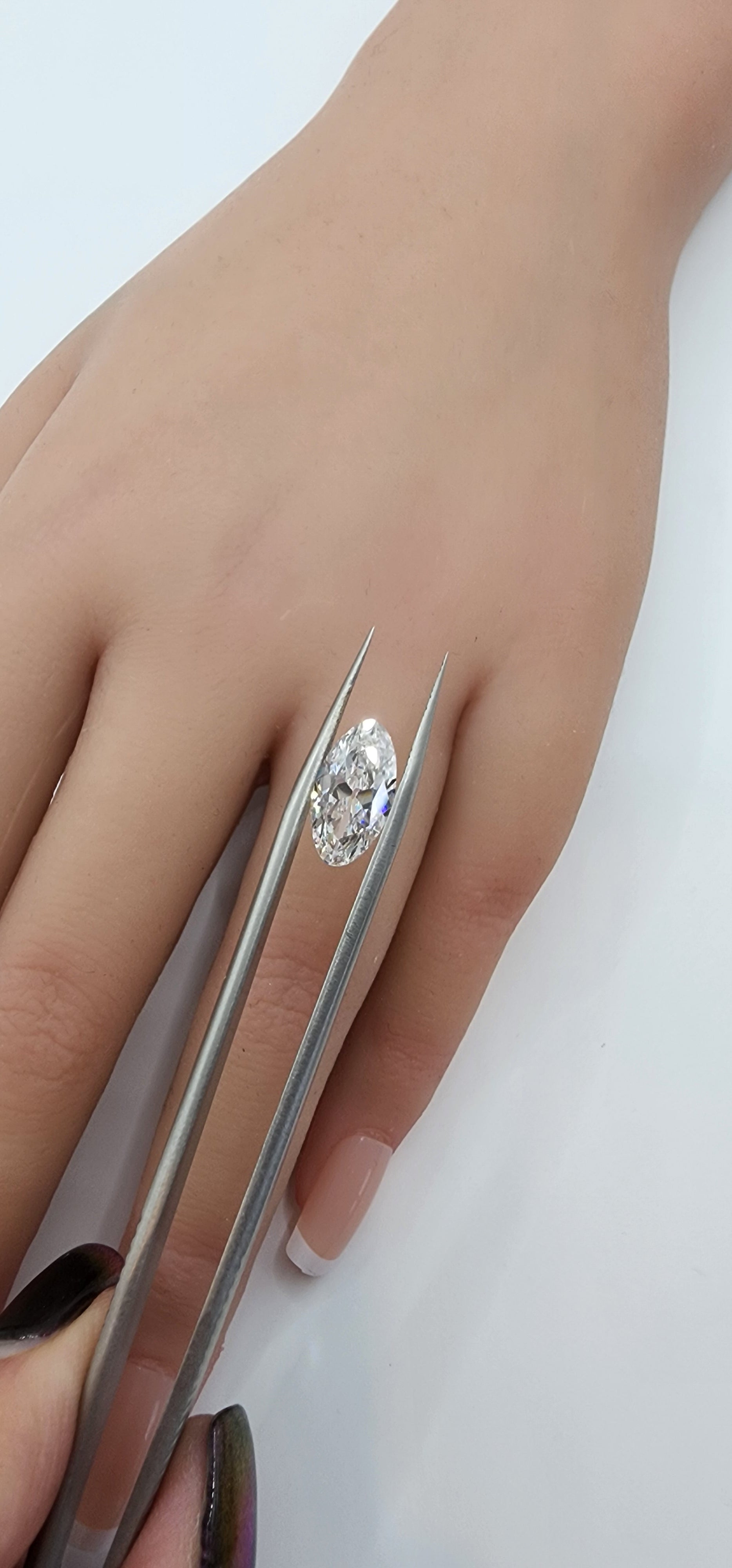 Diamond ring being held with tweezers on a white background