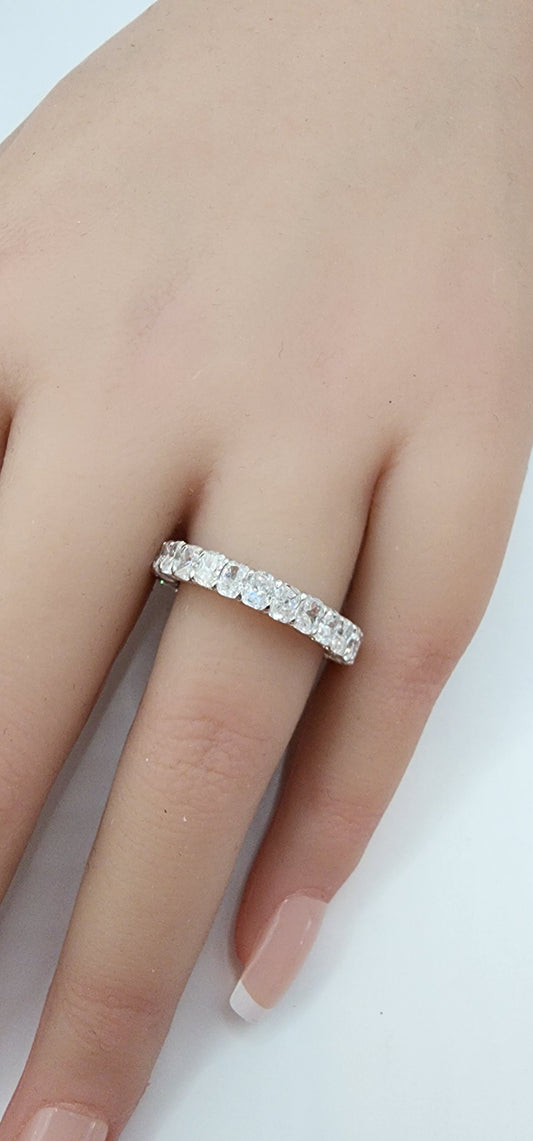 White Gold ring with clear stones on a finger against a white background