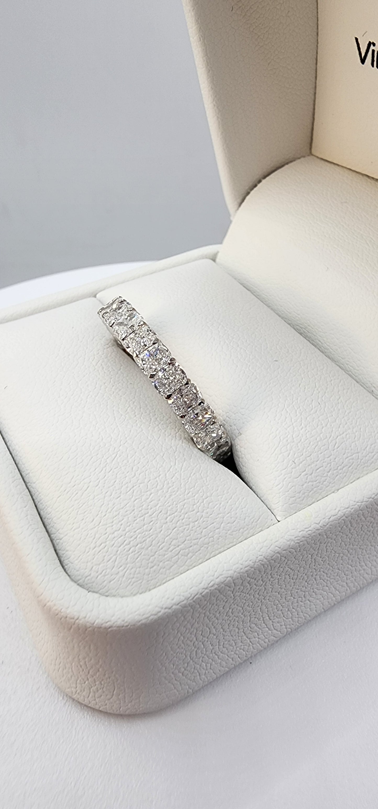 White Gold ring with clear stones on a finger against a white background