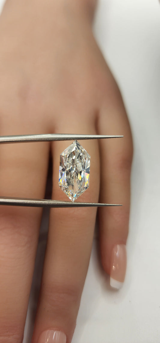 Diamond inside tweezers in front of a hand on  a white background