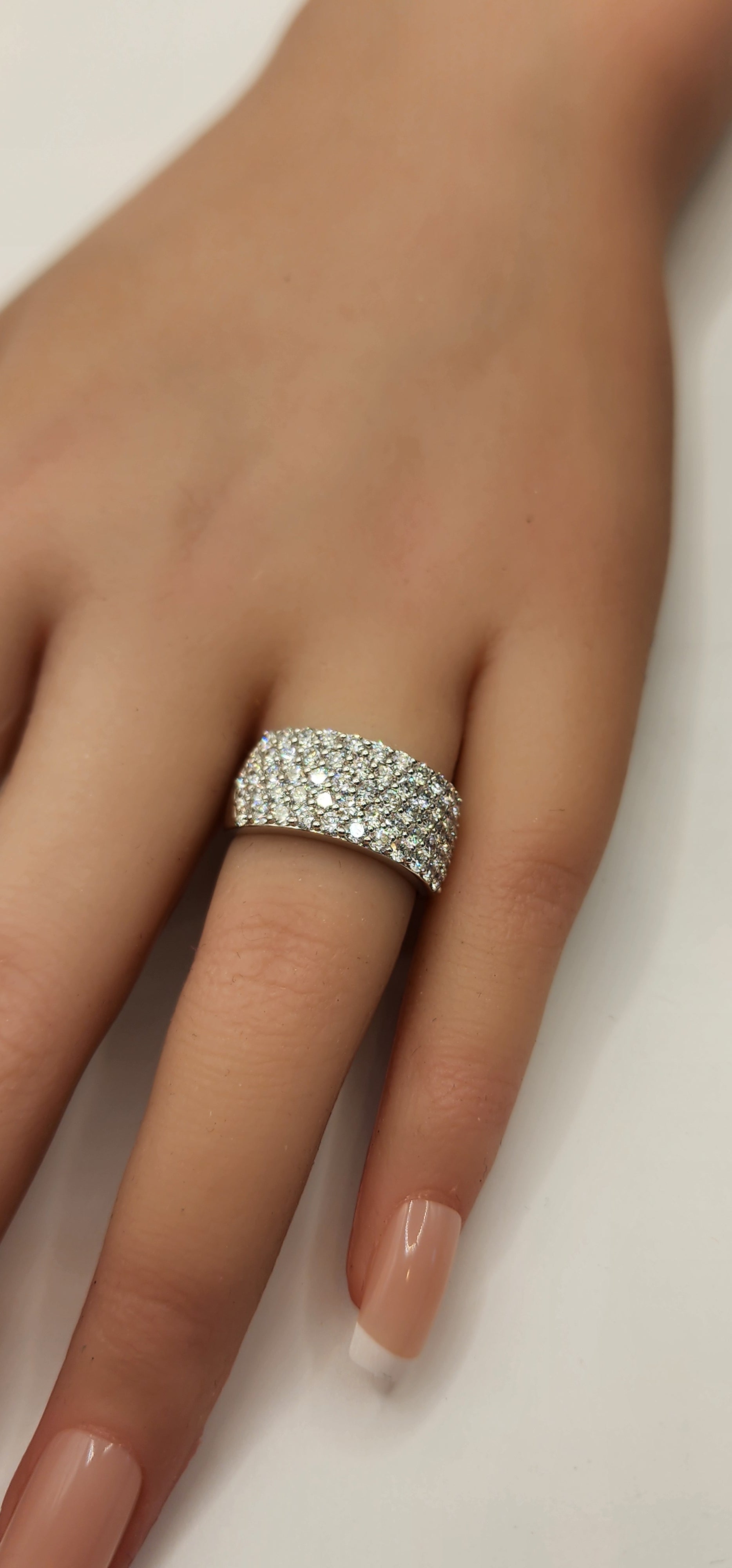 Multi row diamond ring on a hand in front of a white backdrop