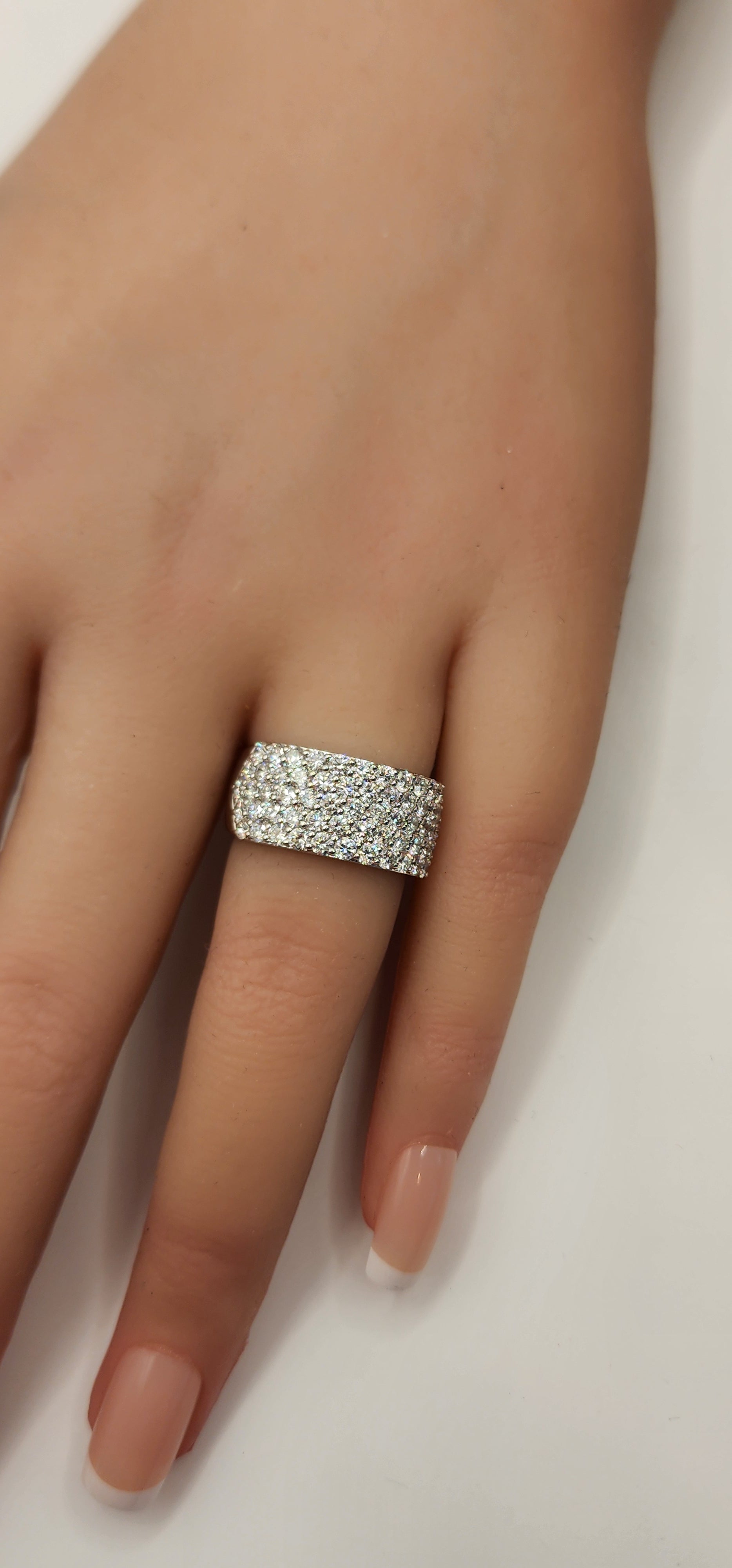 Multi row diamond ring on a hand in front of a white backdrop