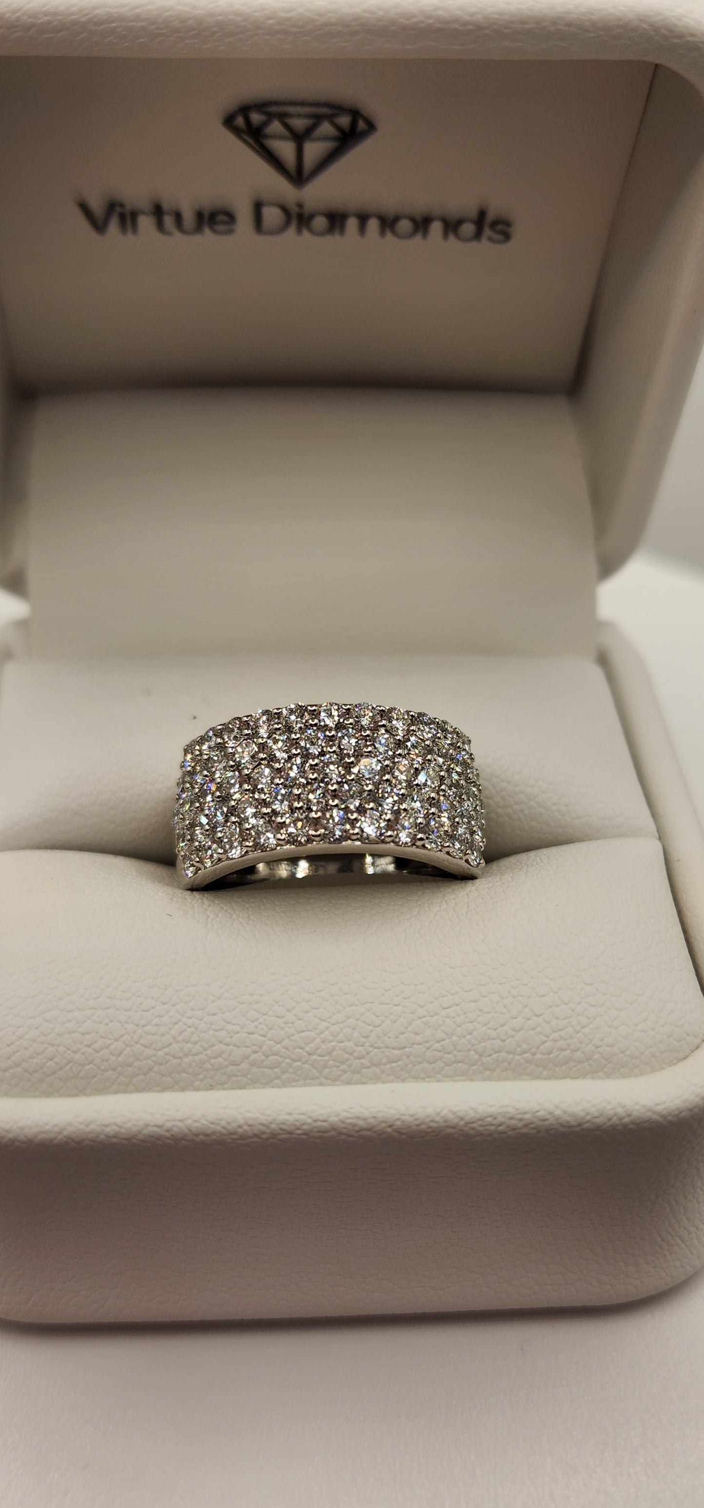 Multi-row diamond ring in a ring box in front of a grey backdrop
