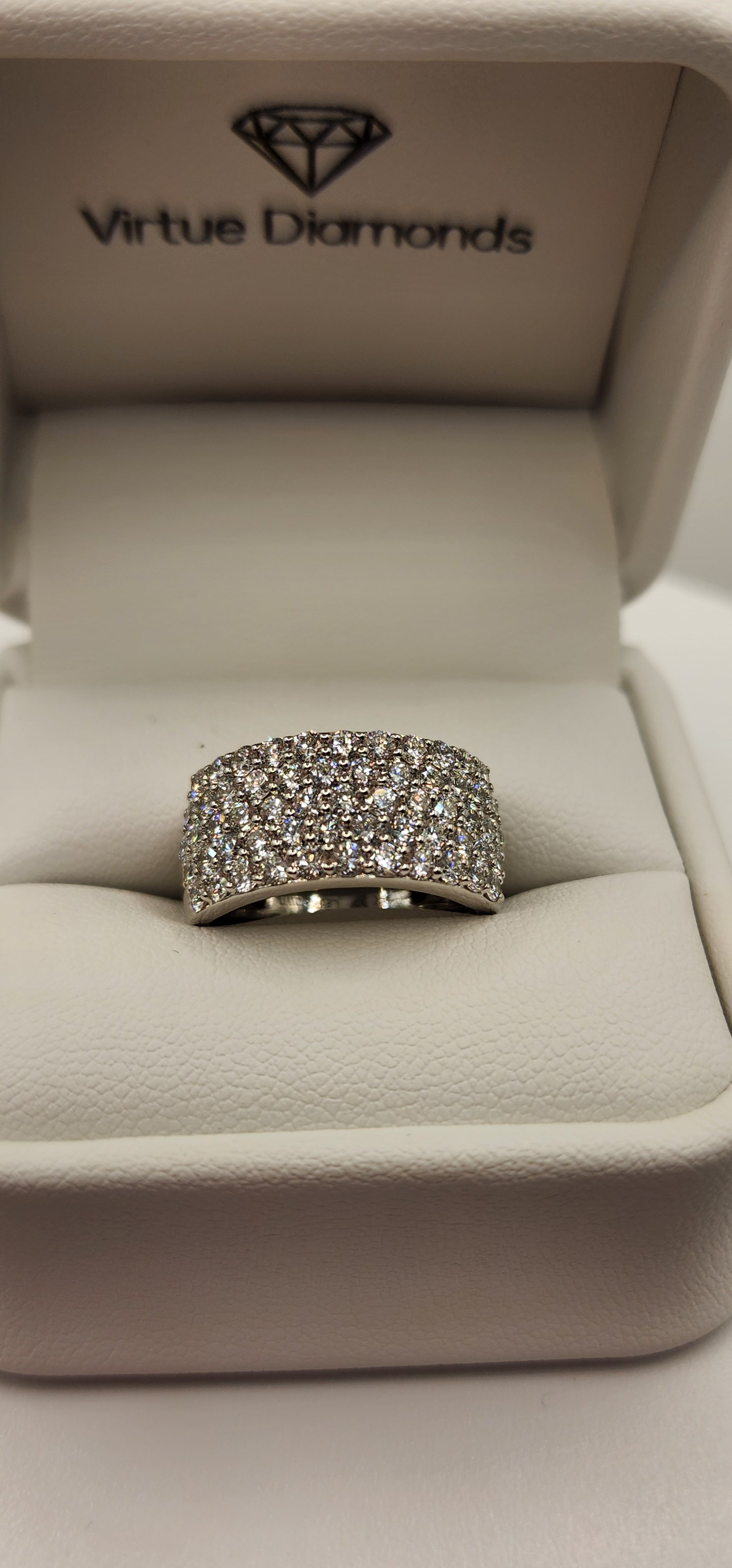 Multi-row diamond ring in a ring box in front of a grey backdrop