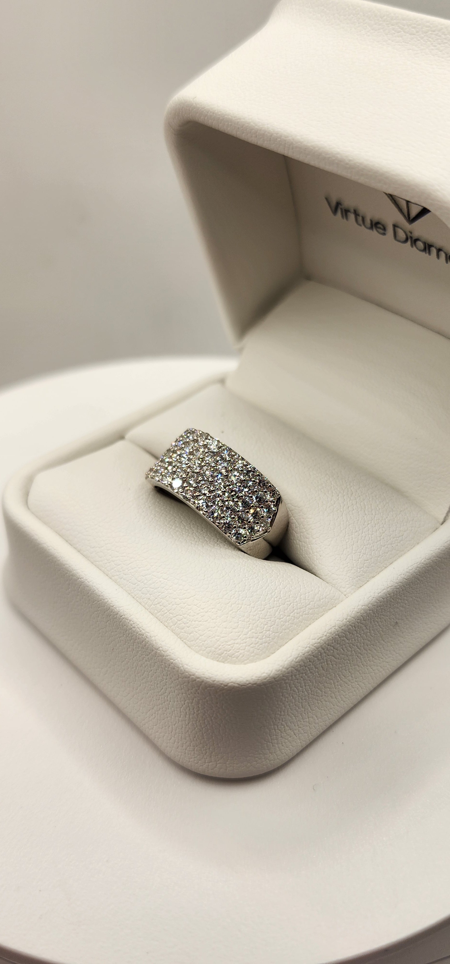 Multi-row diamond ring in a ring box in front of a grey backdrop