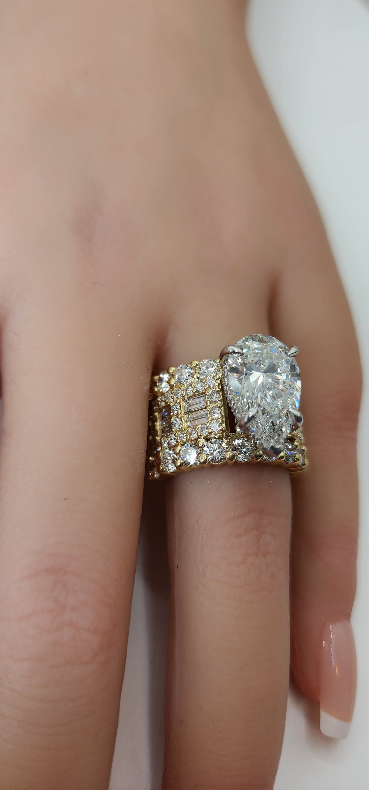 pear diamond ring on a hand against a white background
