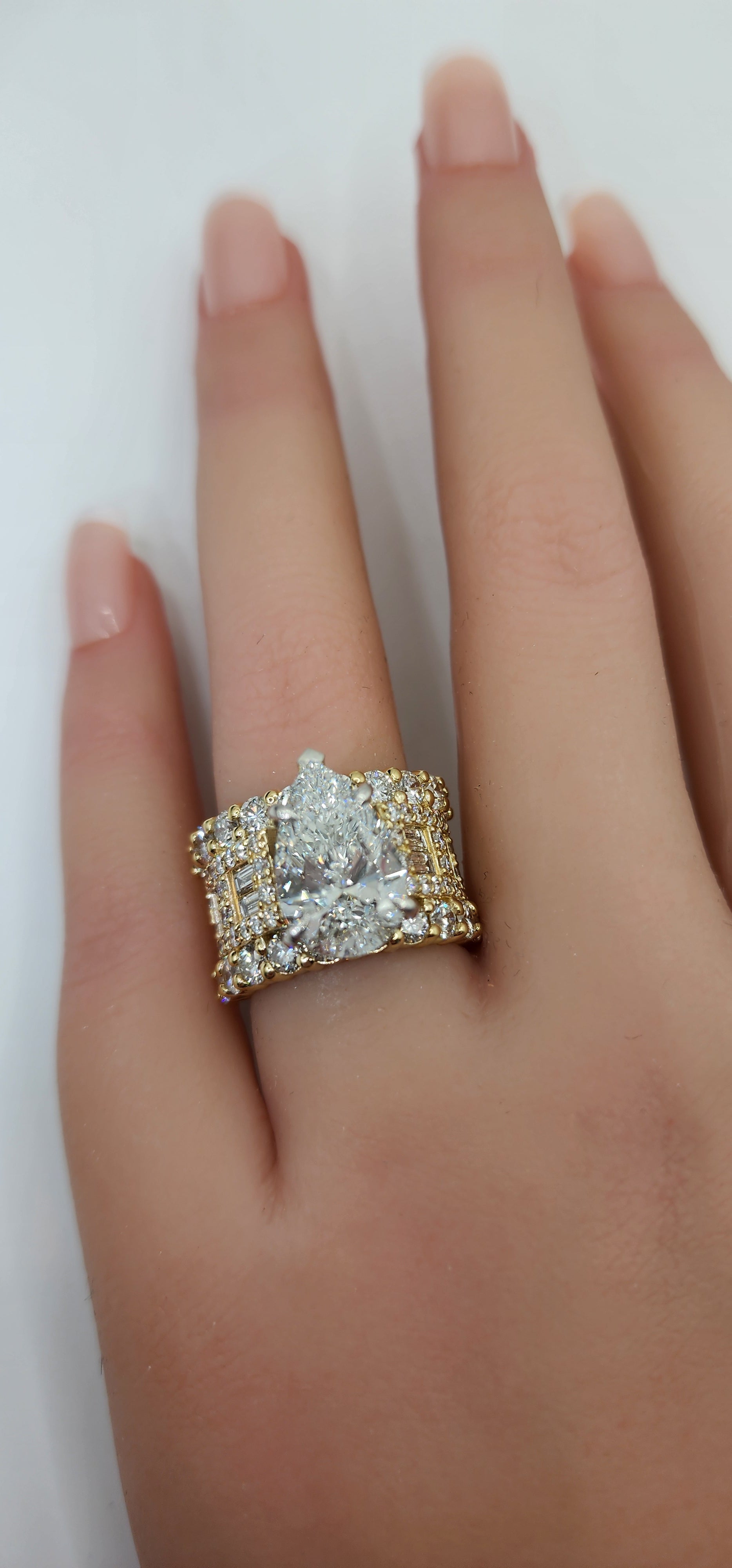 pear diamond ring on a hand against a white background