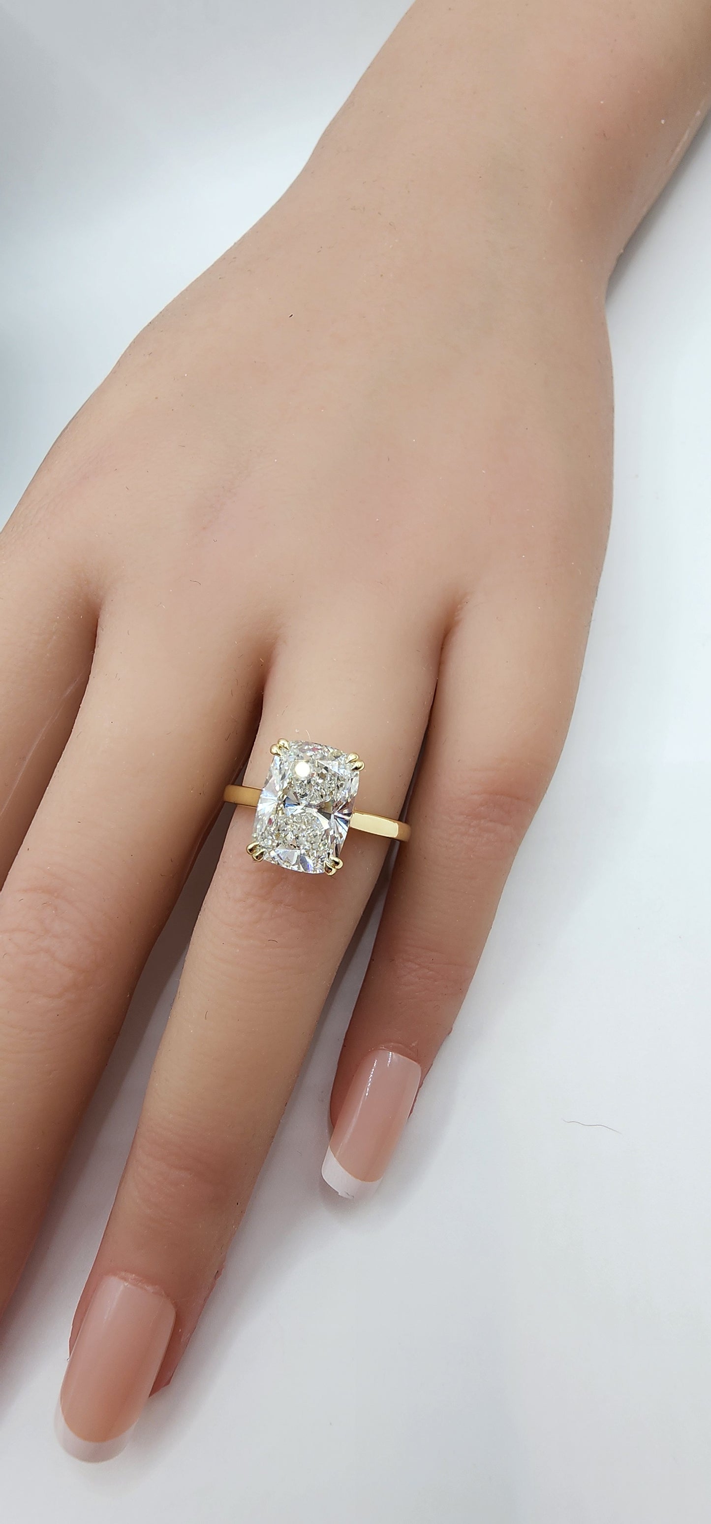 Gold ring with a large diamond on a hand against a white background