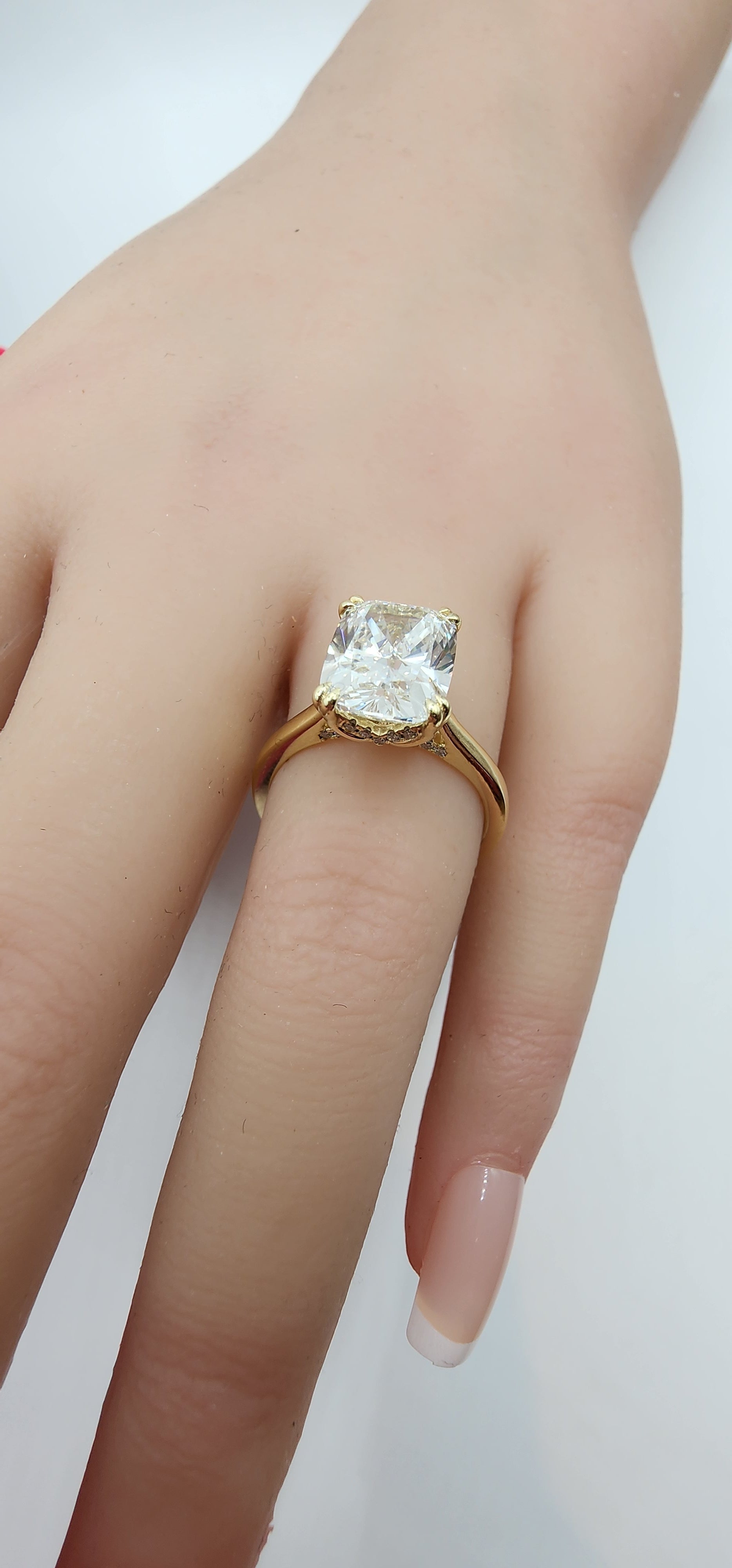 Gold ring with a large diamond on a hand against a white background