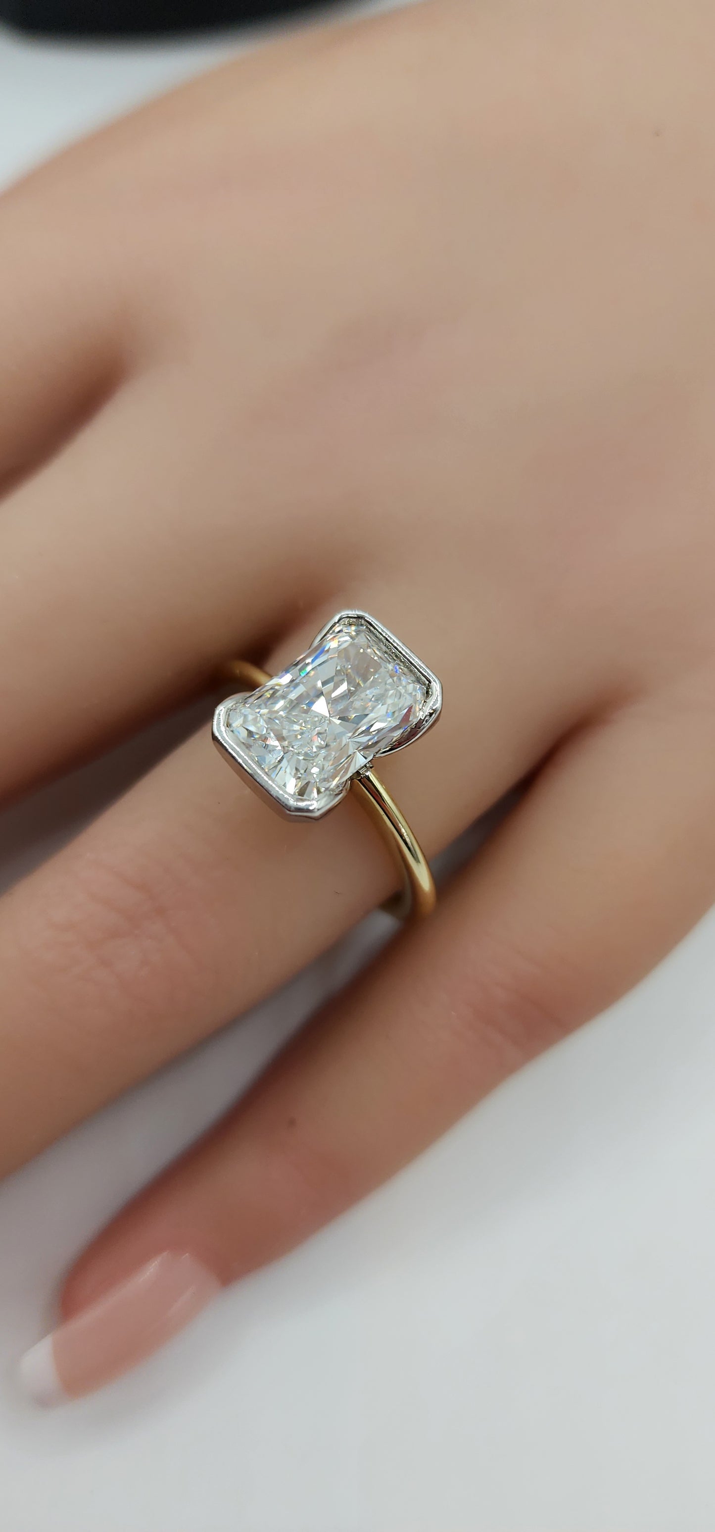 Gold ring with a large diamond on a hand against a white background