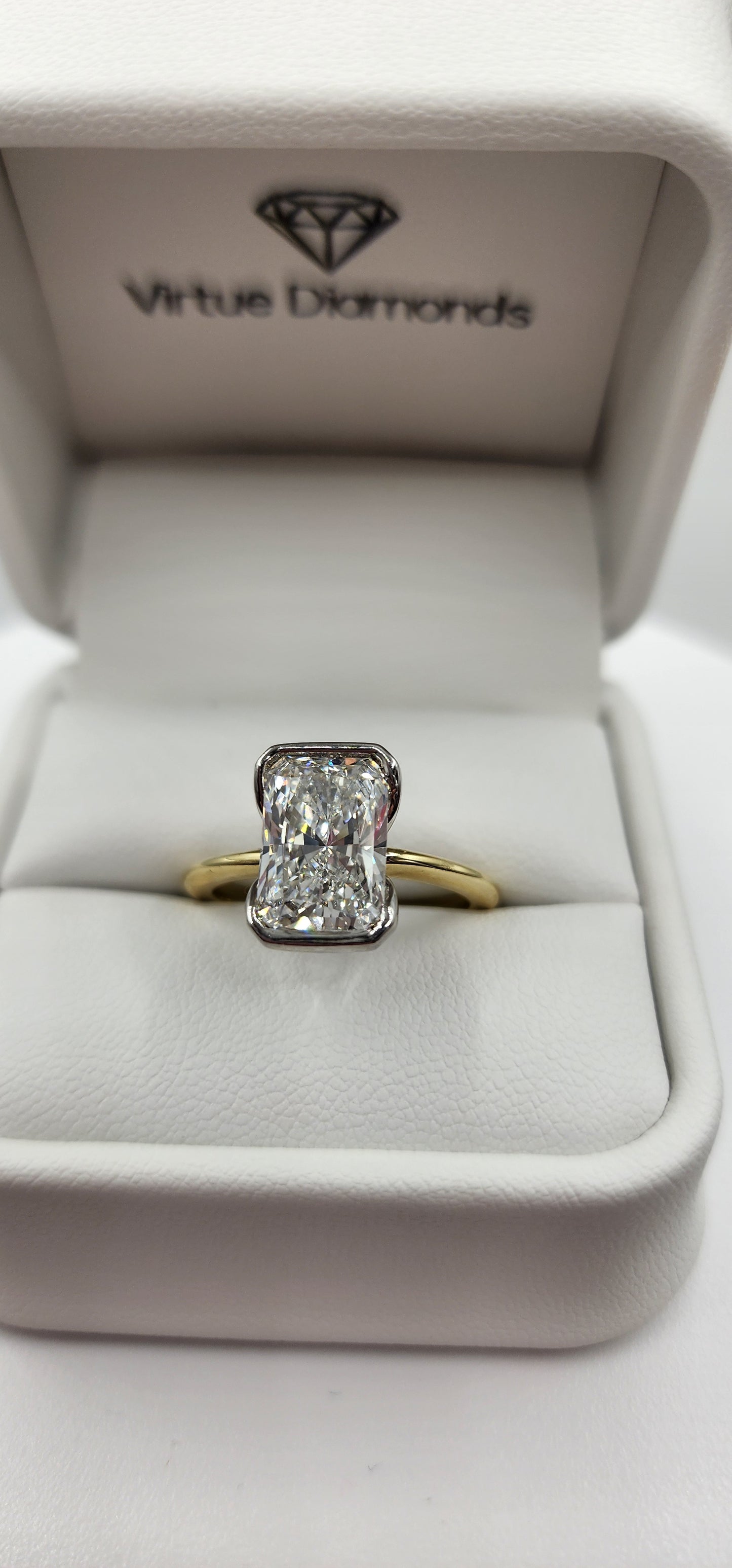 Gold and diamond ring in a white jewelry box with 'Virtue Diamonds' branding.