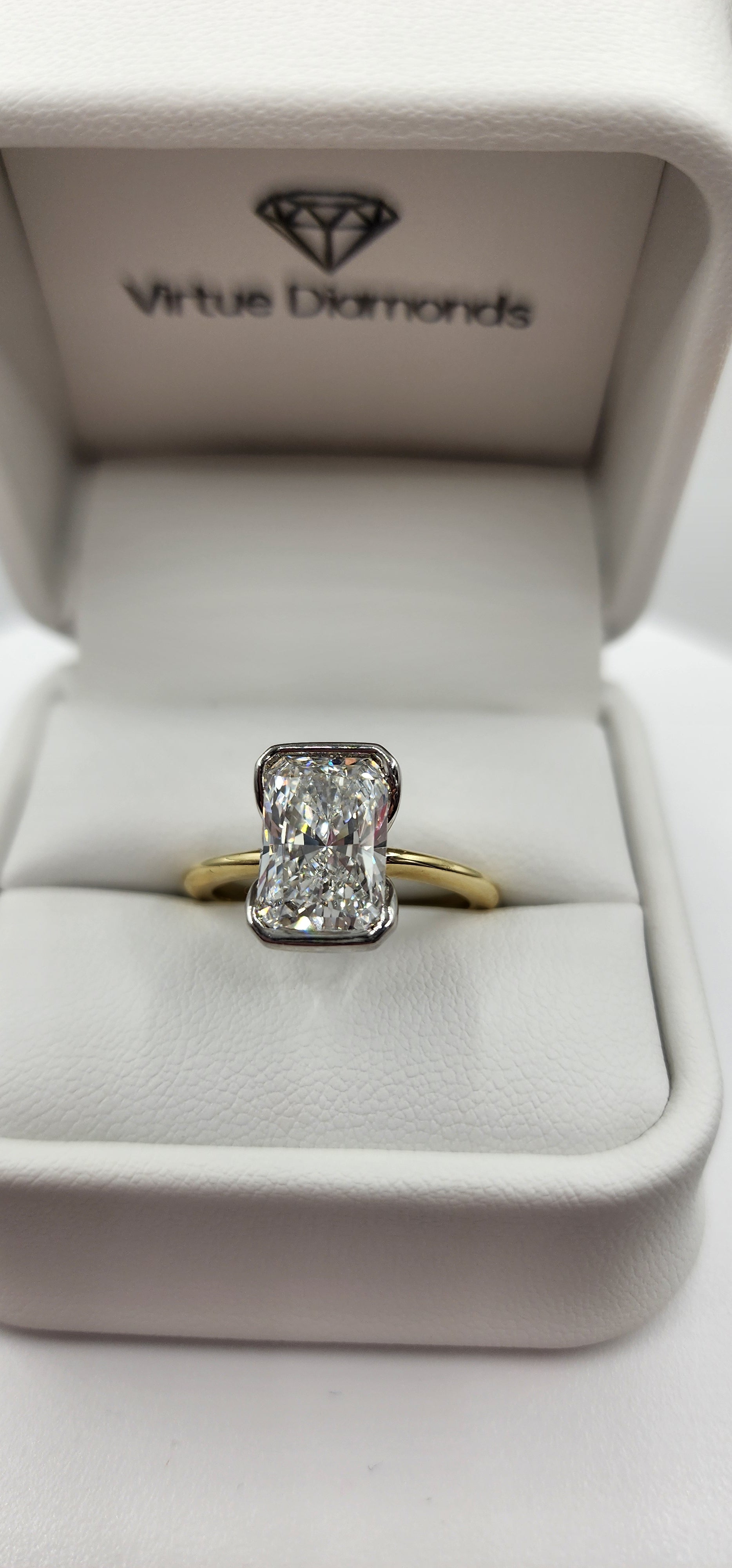 Gold and diamond ring in a white jewelry box with 'Virtue Diamonds' branding.