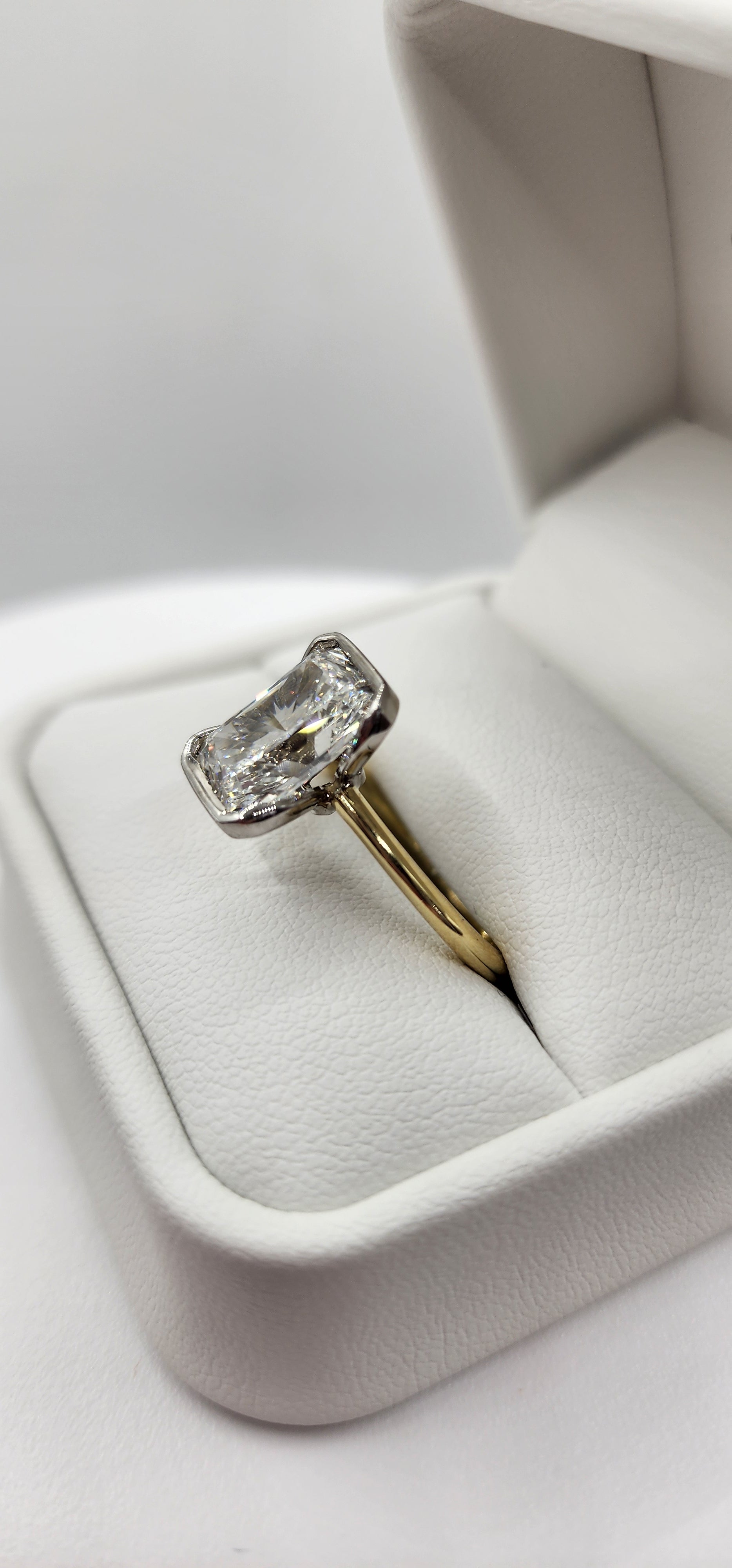 Gold ring with a diamond in a white jewelry box