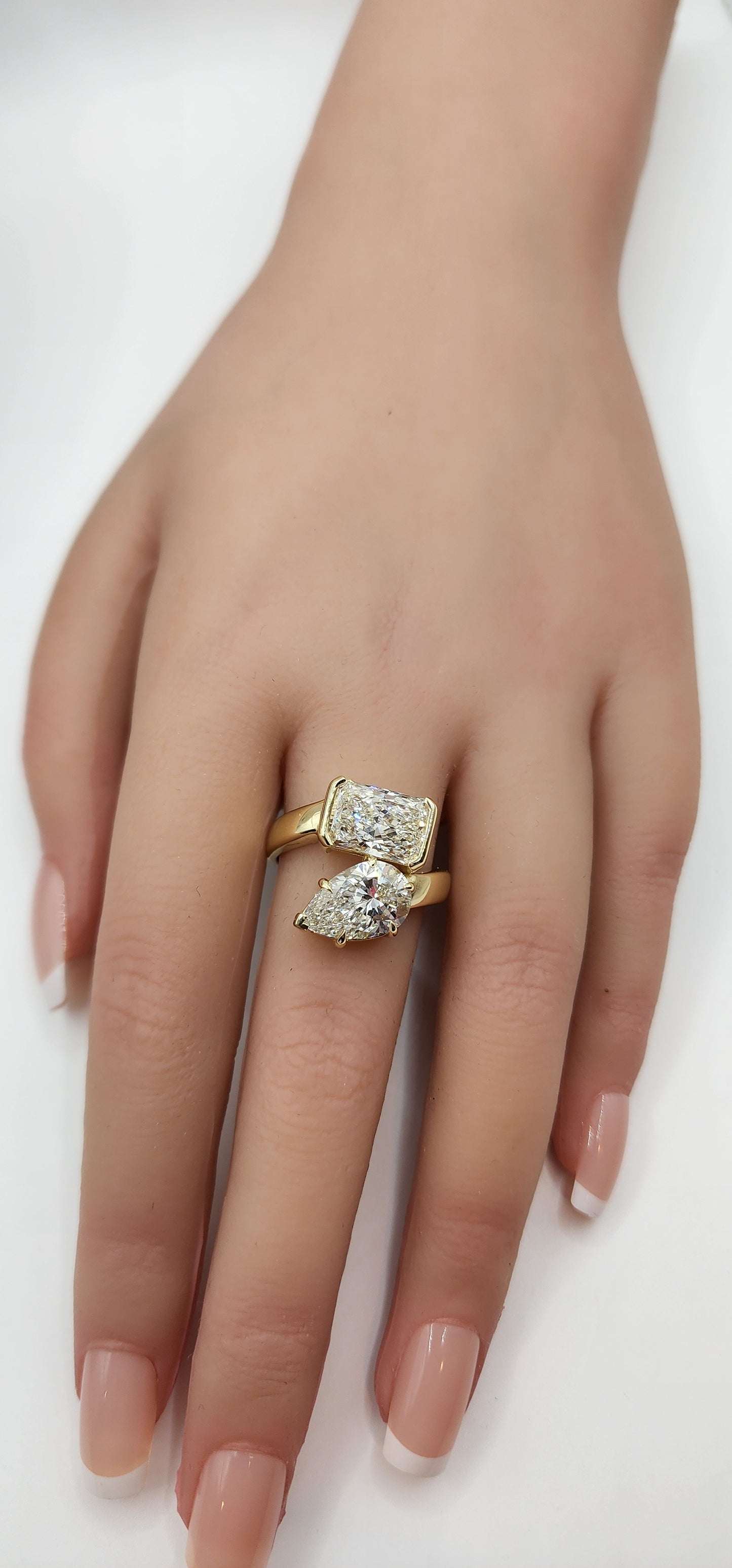 Hand wearing a gold ring with a diamond design on a white background