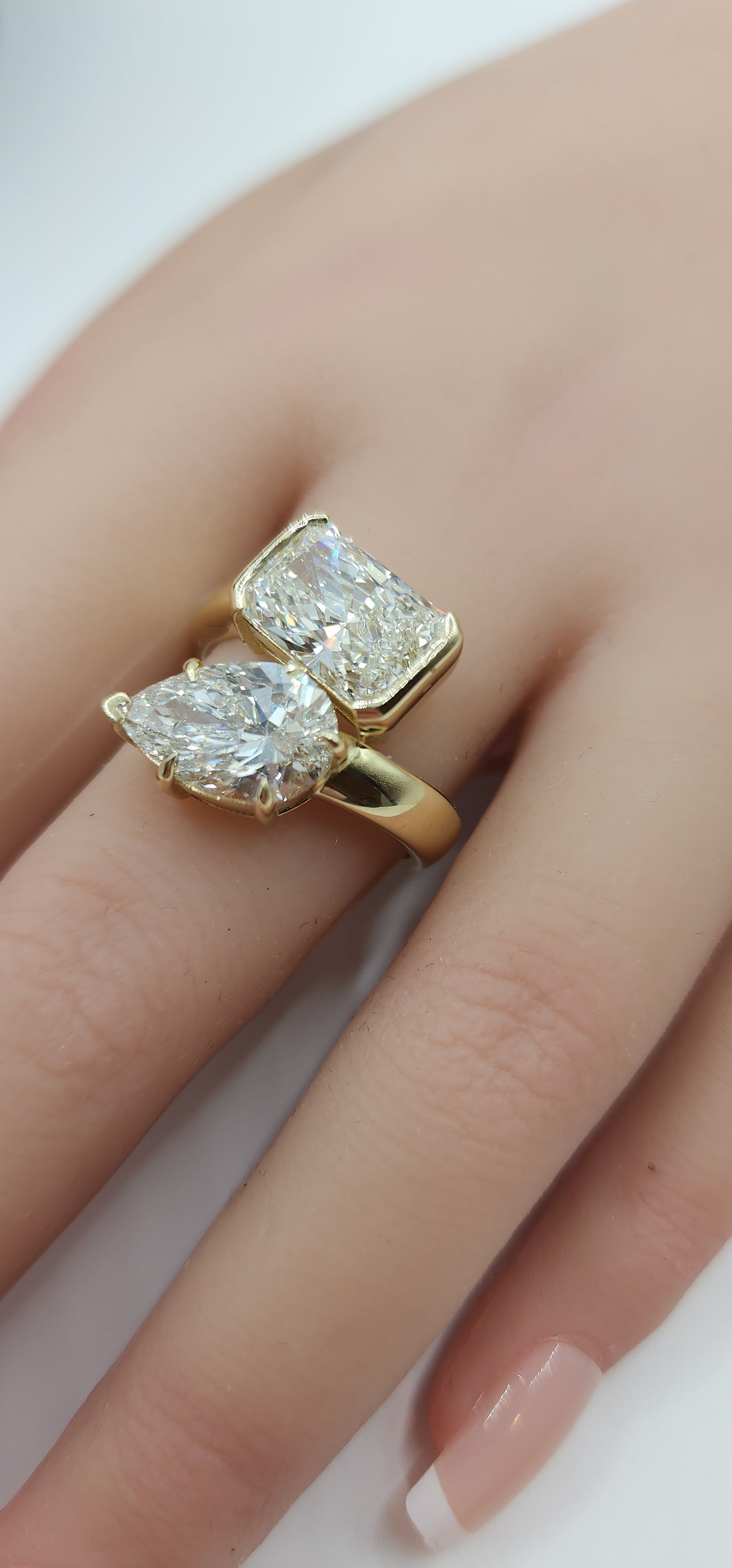Gold ring with two diamonds on a hand against a neutral background