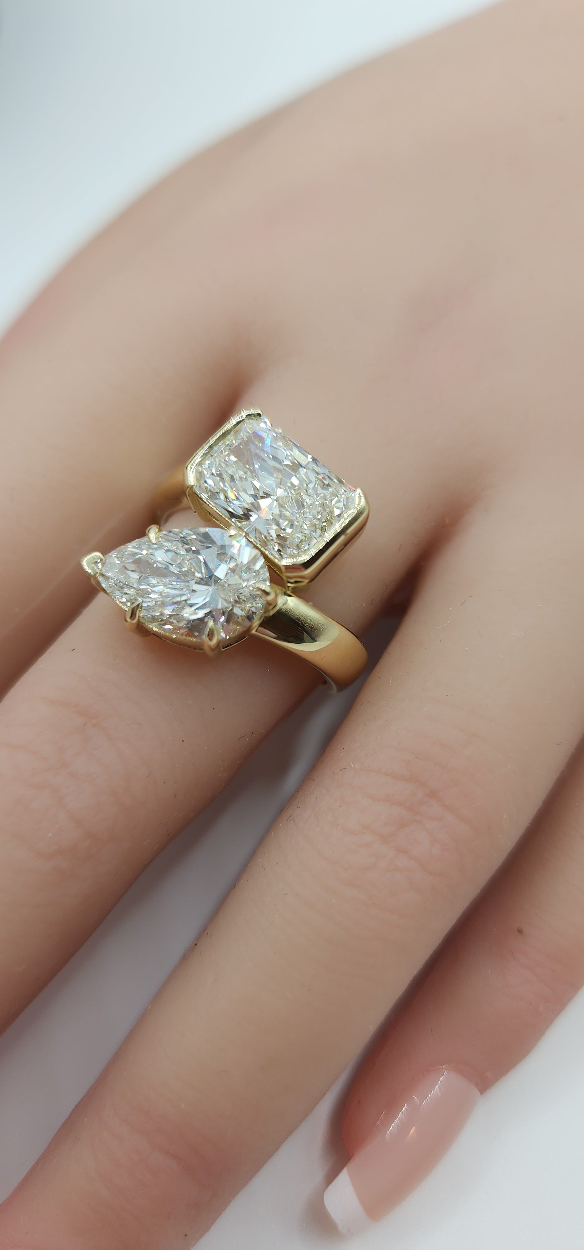 Gold ring with two diamonds on a hand against a neutral background