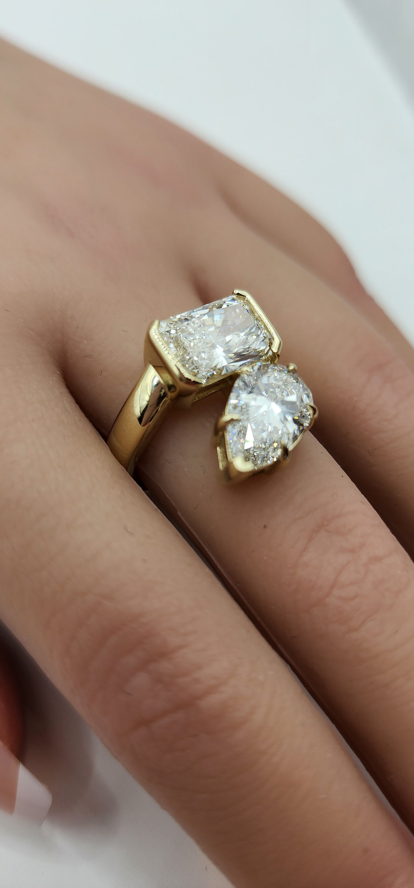 Gold ring with two large diamonds on a hand against a white background