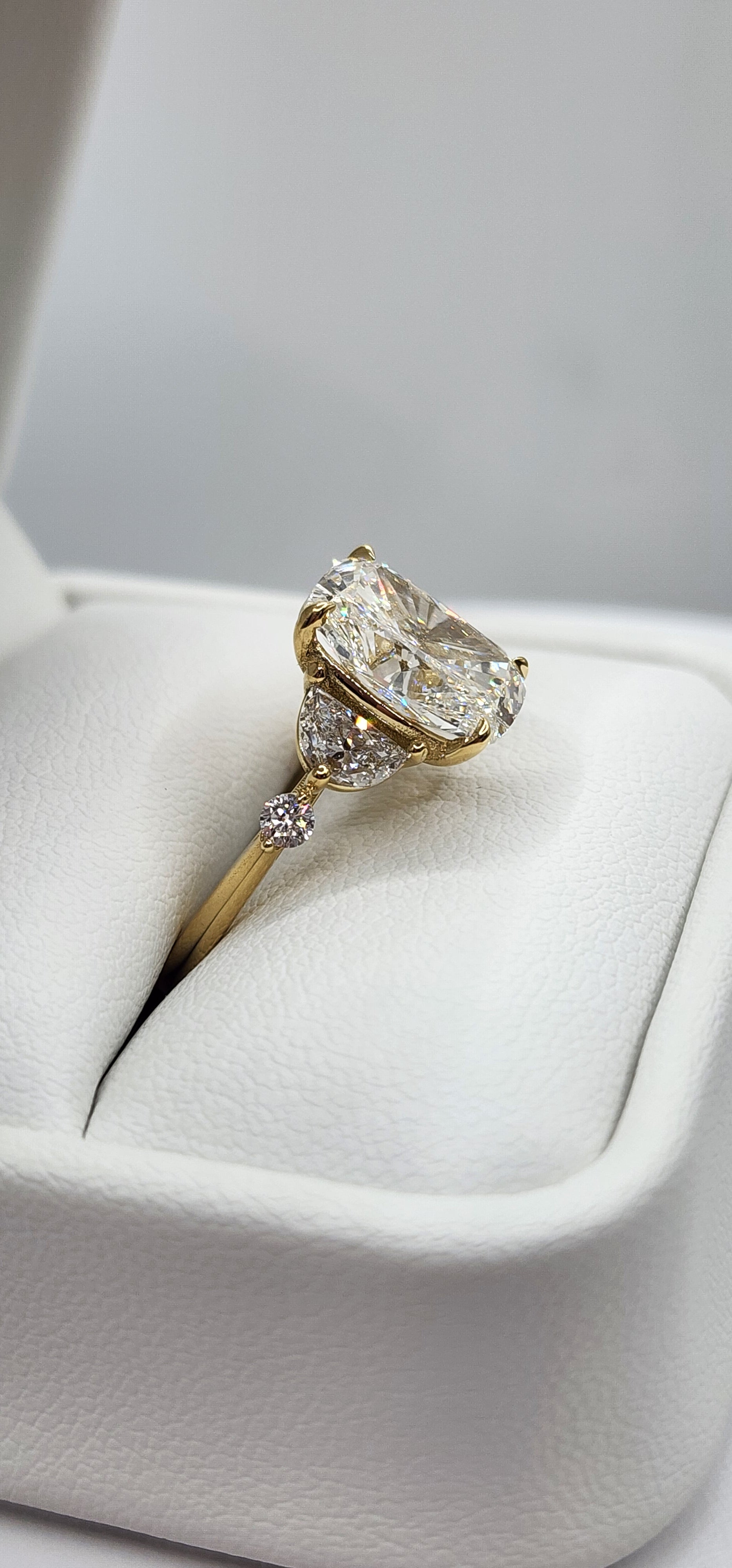 Gold ring with a large diamond on a white cushion