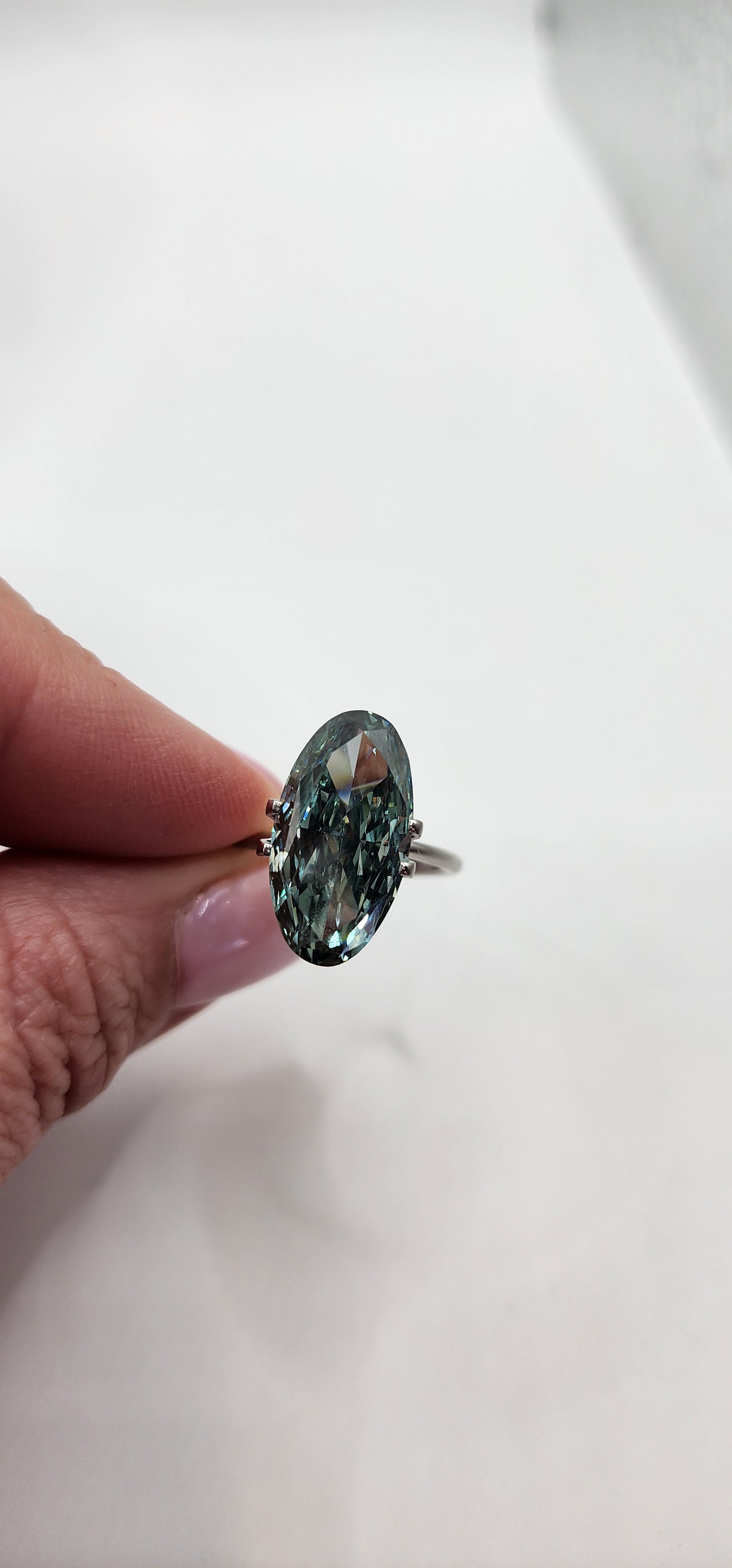 Hand holding a green gemstone against a white background
