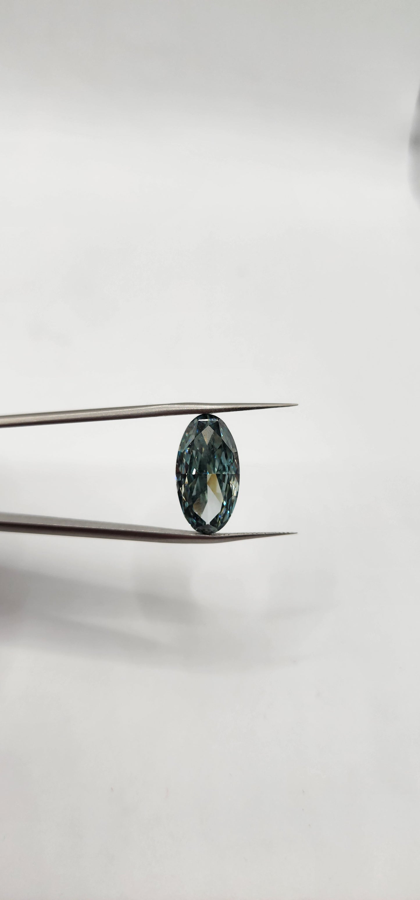 Close-up of a gemstone on tweezers against a white background