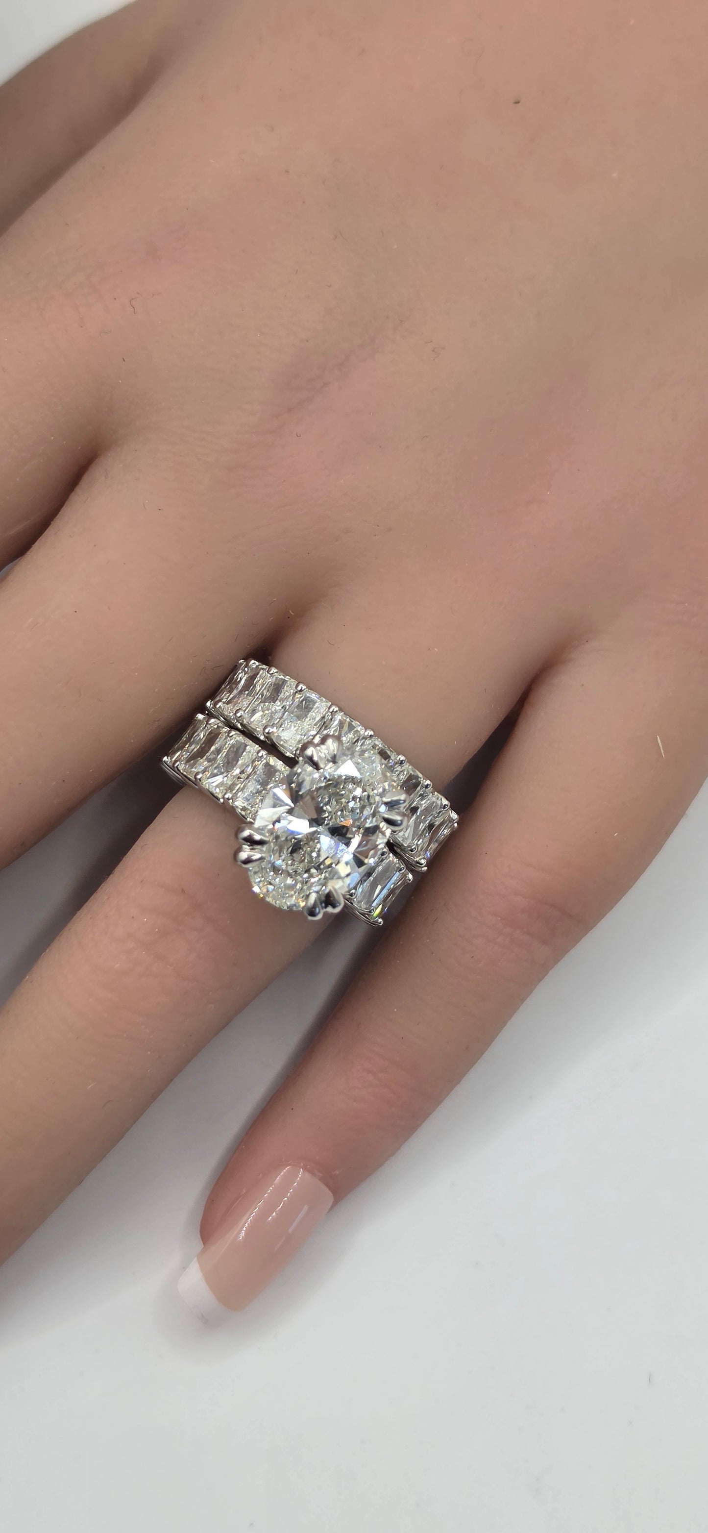 Close-up of a hand wearing a diamond ring on a white background