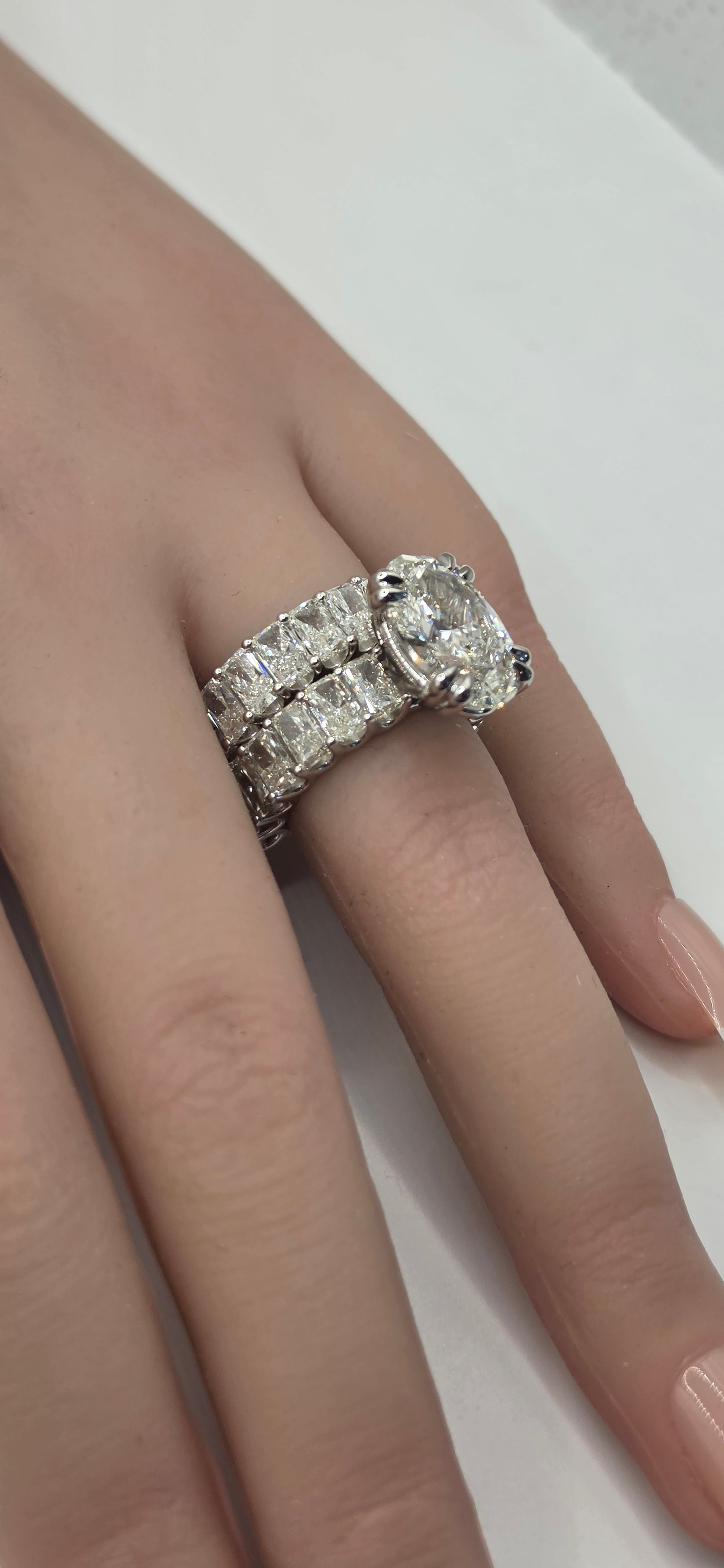 Diamond ring on a finger against a neutral background