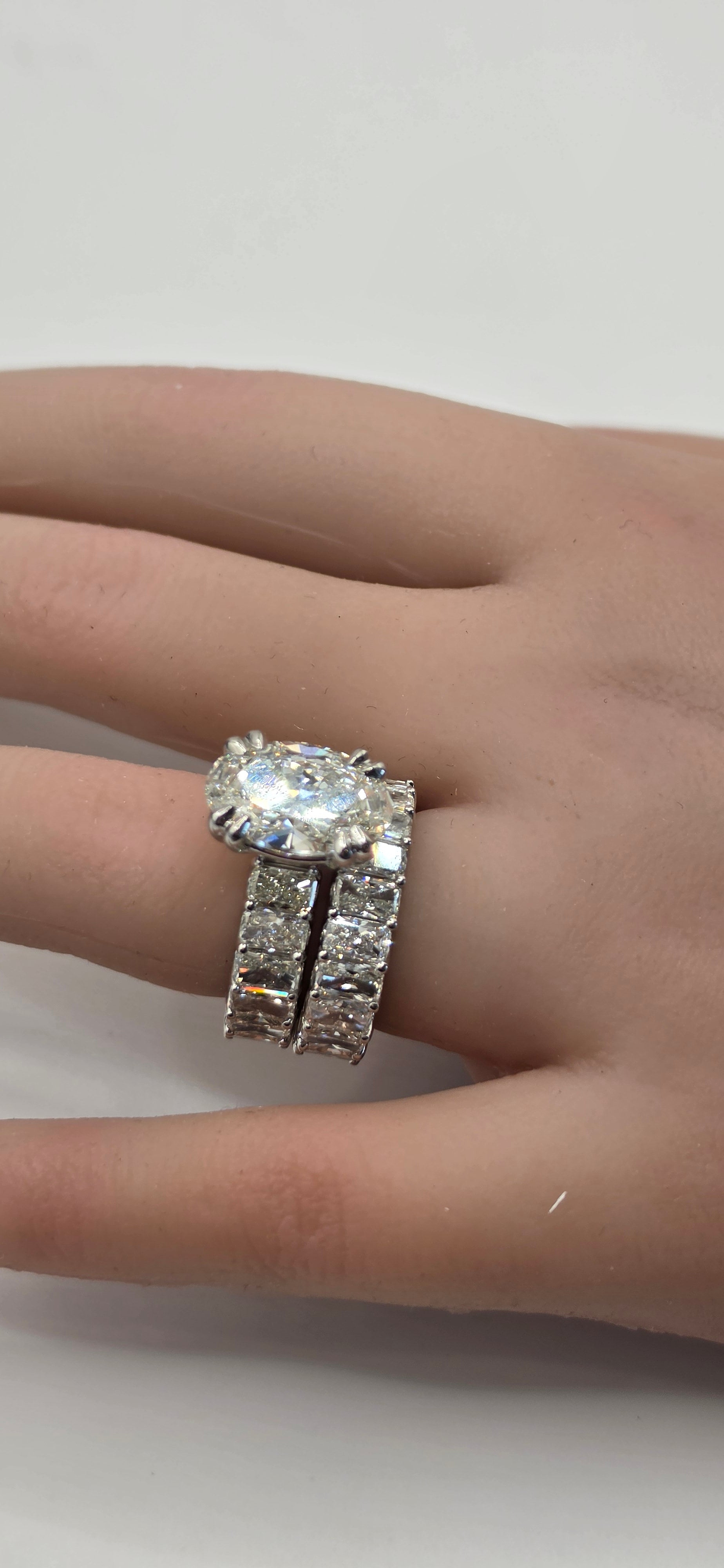 Silver ring with a large central stone on a finger against a neutral background