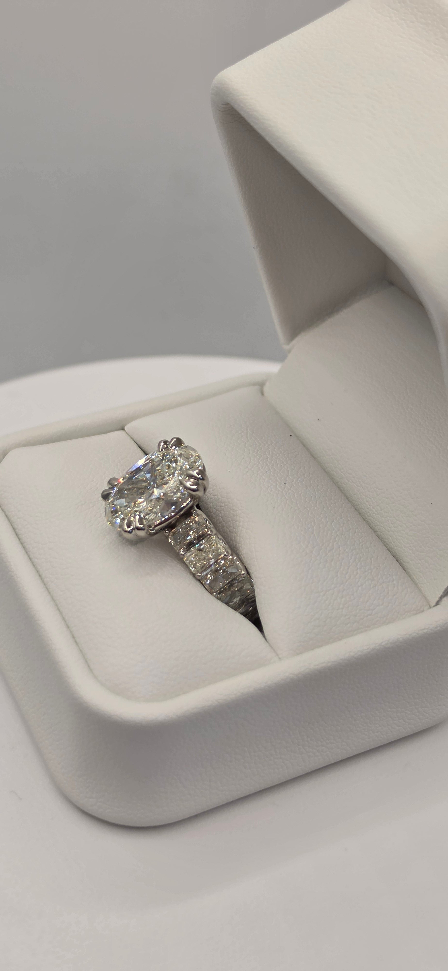 Diamond ring in a white jewelry box on a light gray background