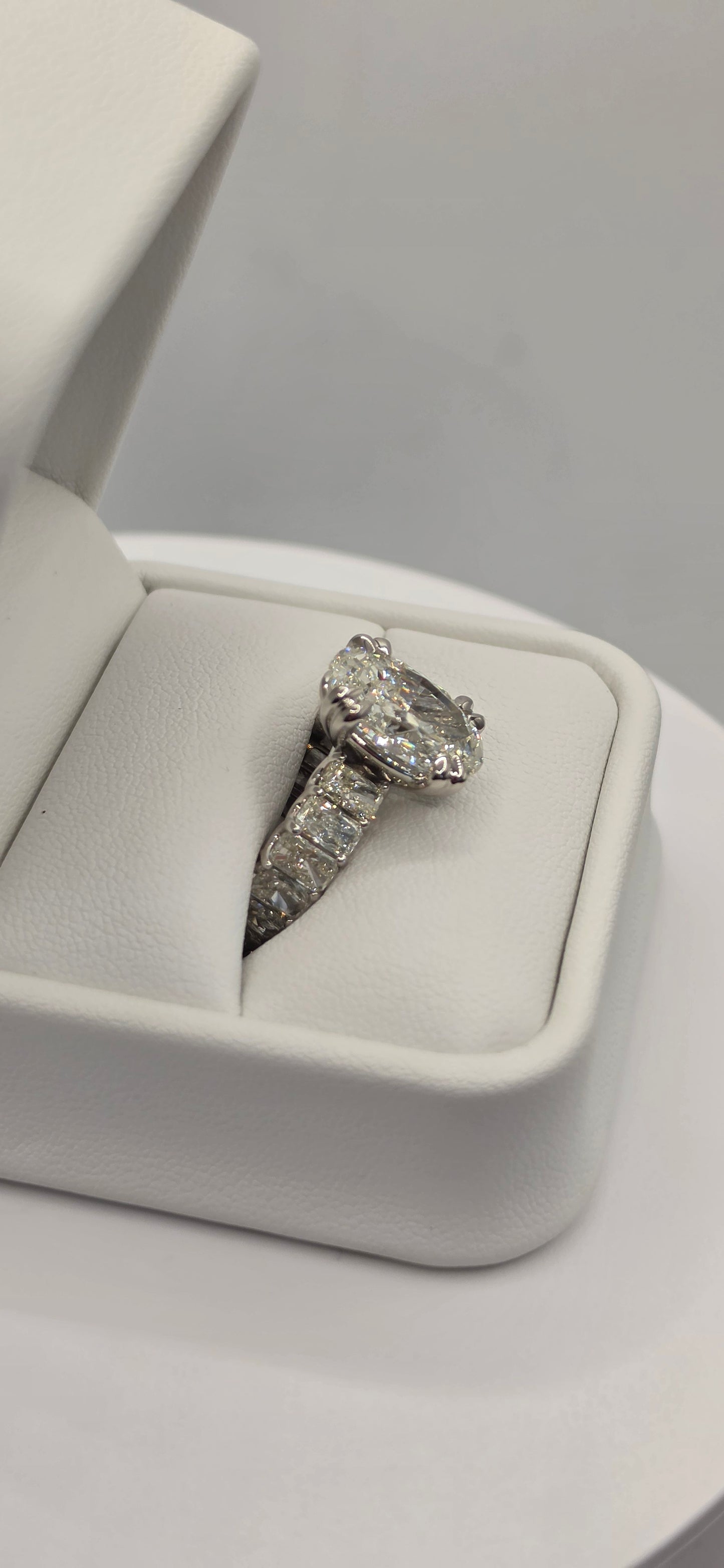 Diamond ring in an open jewelry box on a light gray background